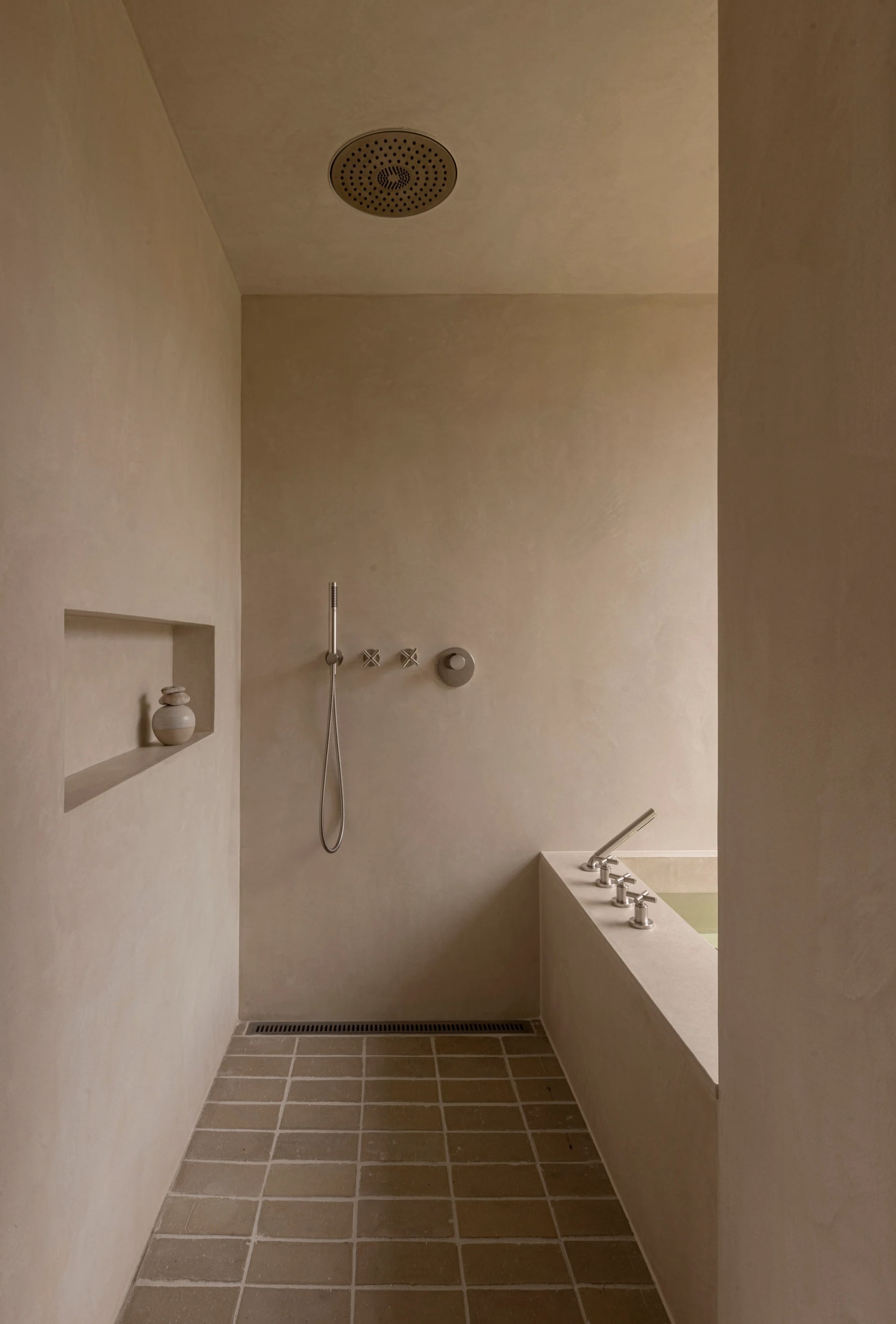 A modern minimalist shower stall with concrete walls and floor, featuring a recessed shower head and minimalist fixtures.