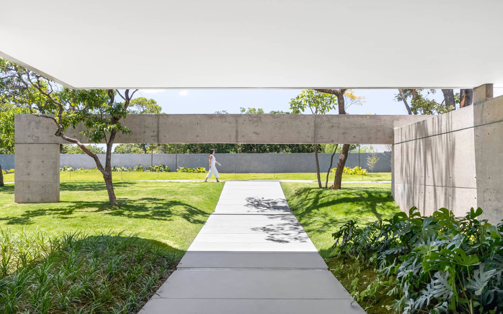 A modern concrete pathway amidst lush greenery, leading to a serene outdoor space.