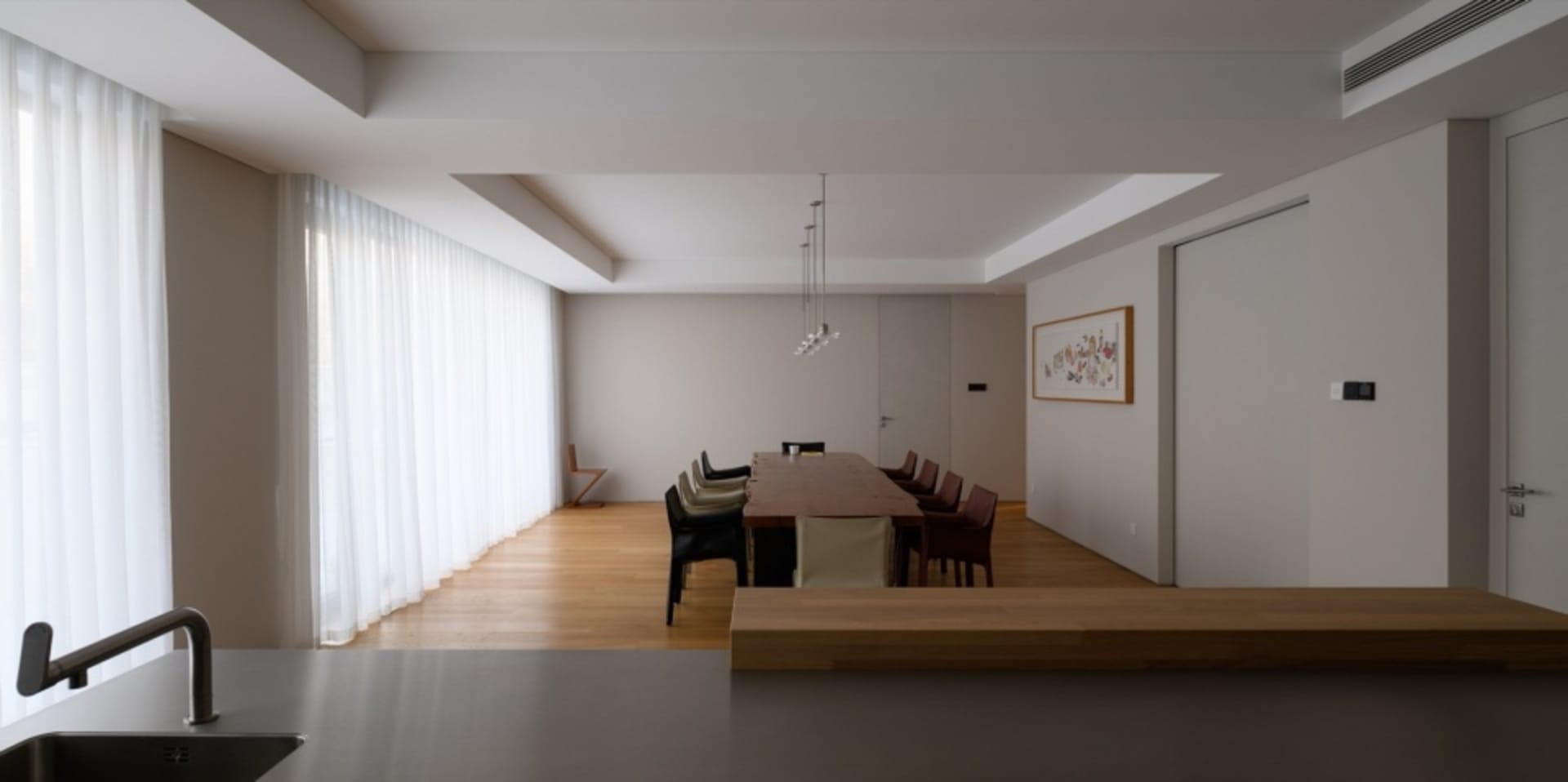 現代簡約餐廳,配有長形木質餐桌、軟墊餐椅與吊燈照明。