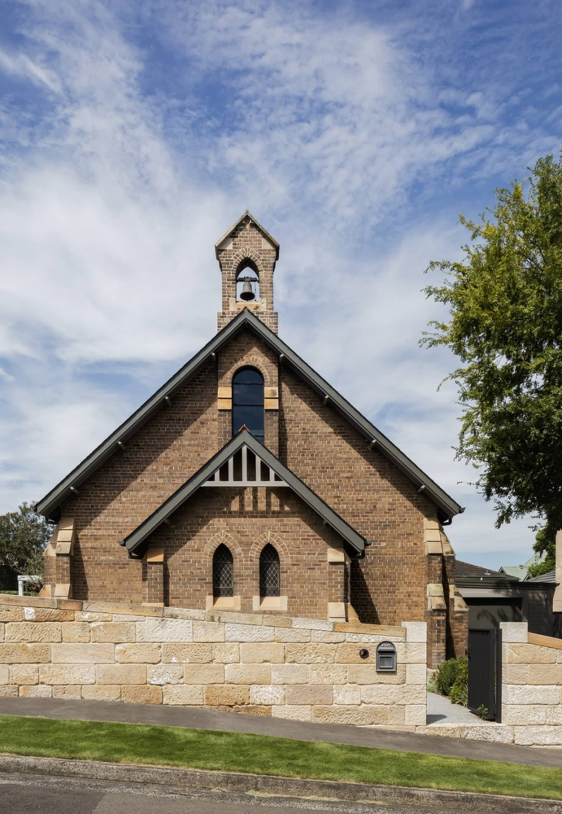 A brick church with a bell tower and large windows.