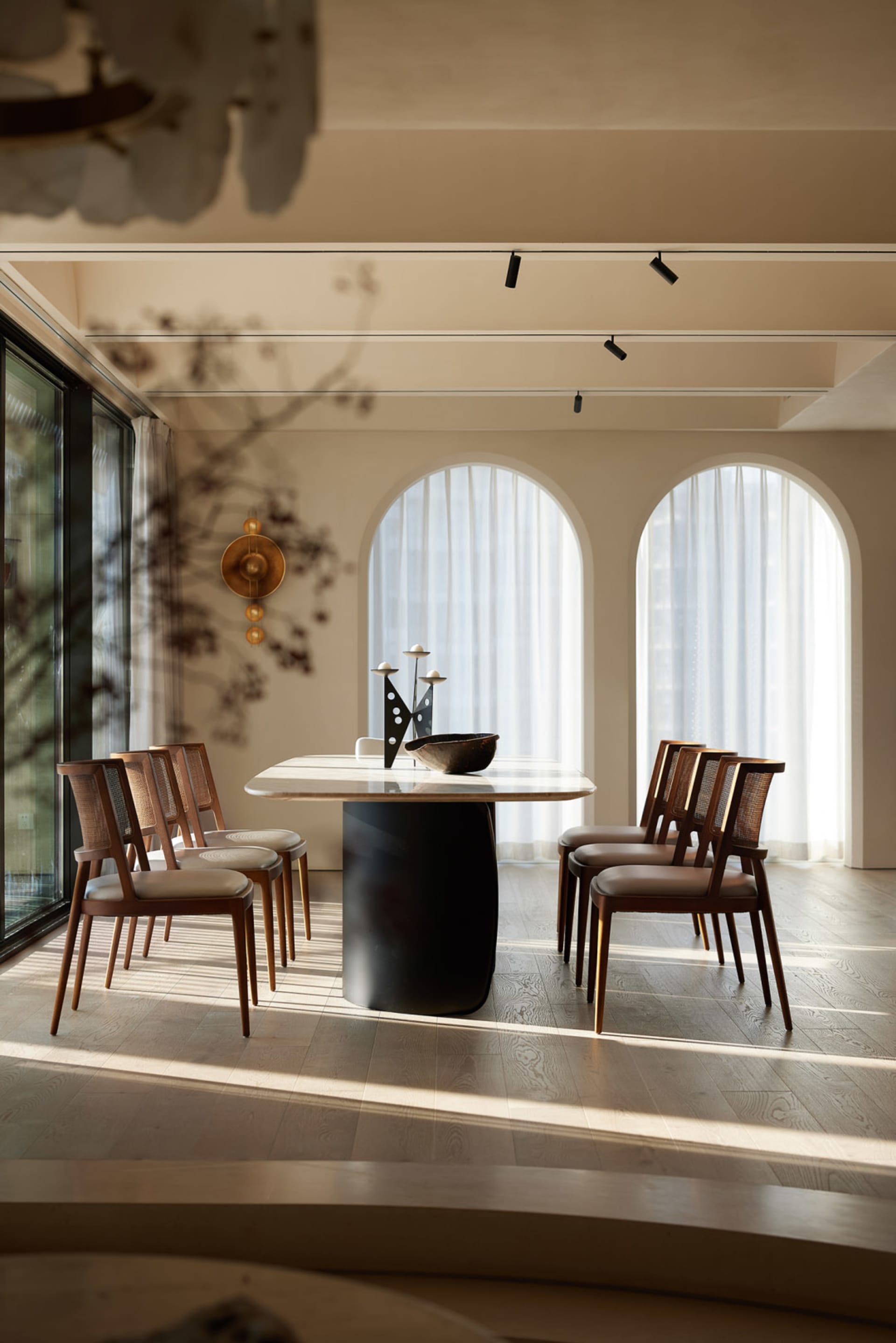 A modern dining room featuring a marble table and wooden chairs with a sleek, minimalist design.