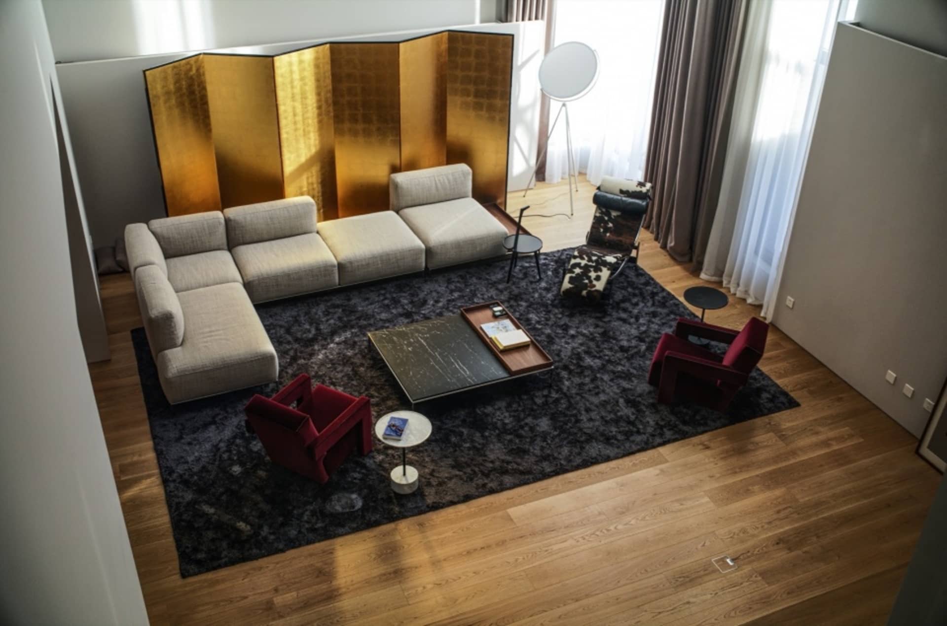 Modern living room featuring a comfortable sofa, armchairs, a coffee table, and a decorative copper screen.