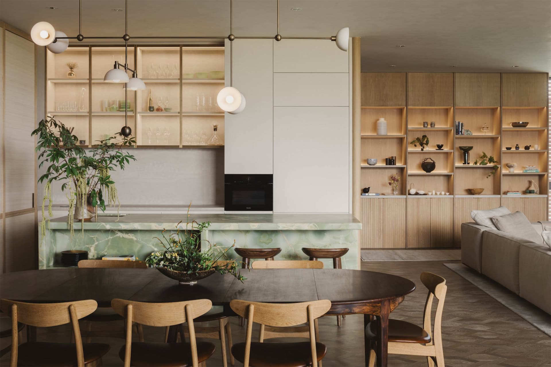 A modern residential kitchen with a marble countertop and wooden furniture.