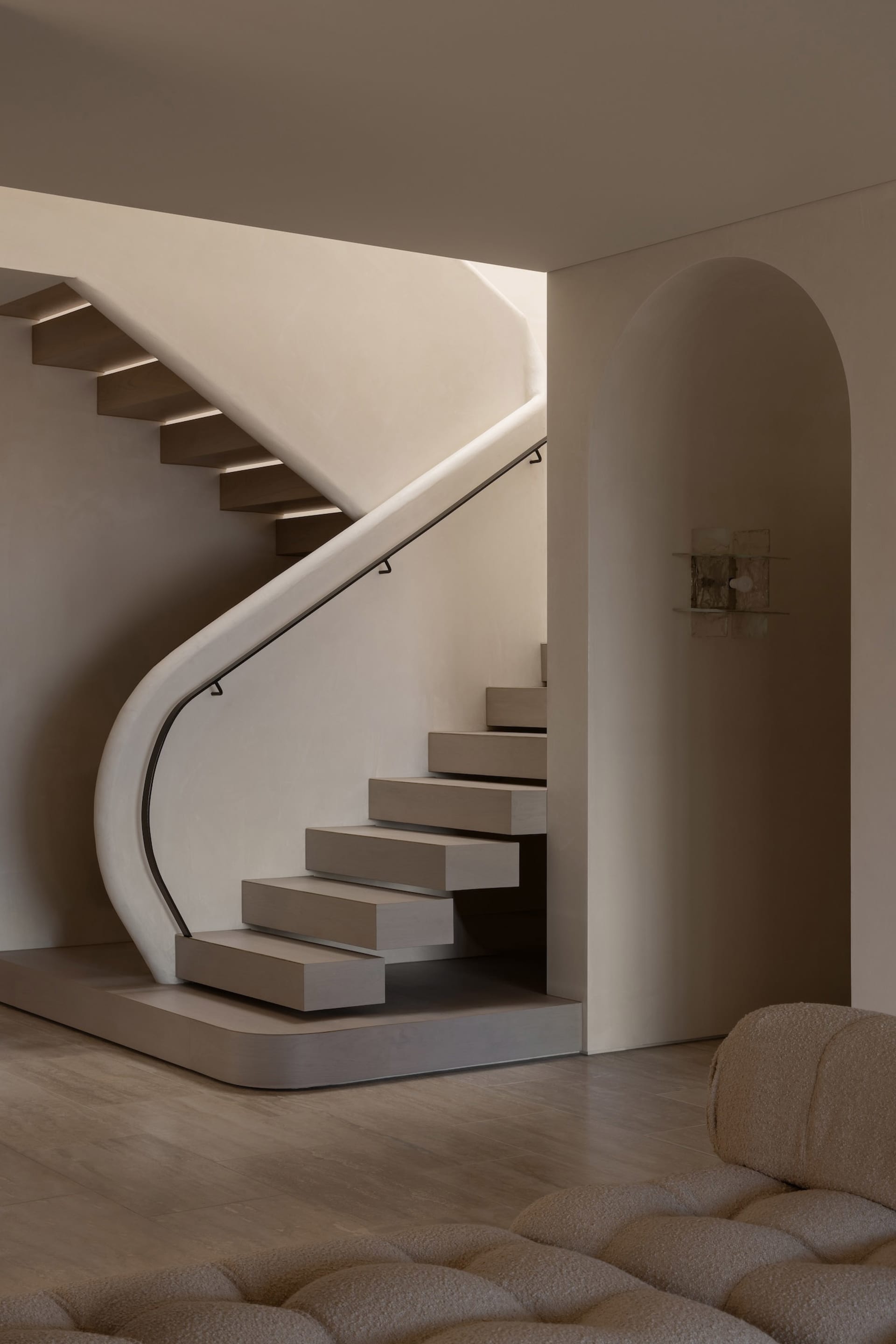 A minimalist staircase with wooden steps and a concrete wall, featuring a modern railing and a well-lit space.