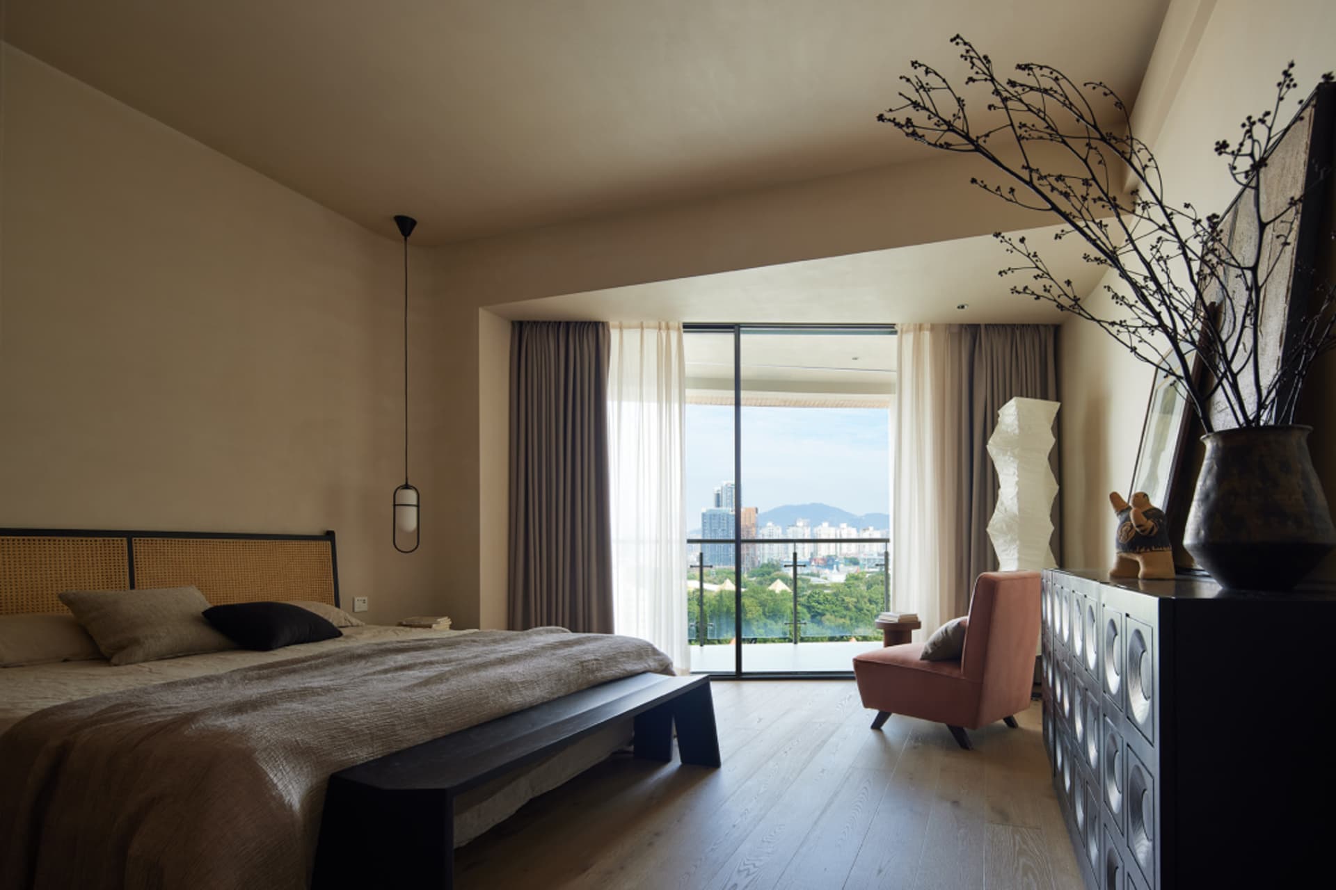 A modern bedroom featuring neutral-toned interior design with a minimalist approach, large windows overlooking a cityscape, a