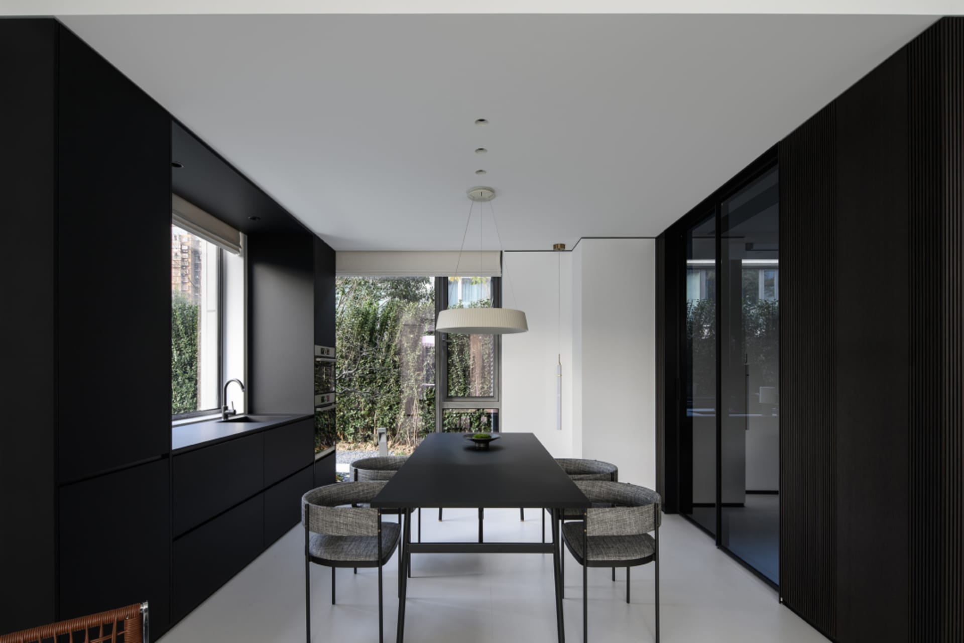 Modern black kitchen and dining room interior with dark wood accents.