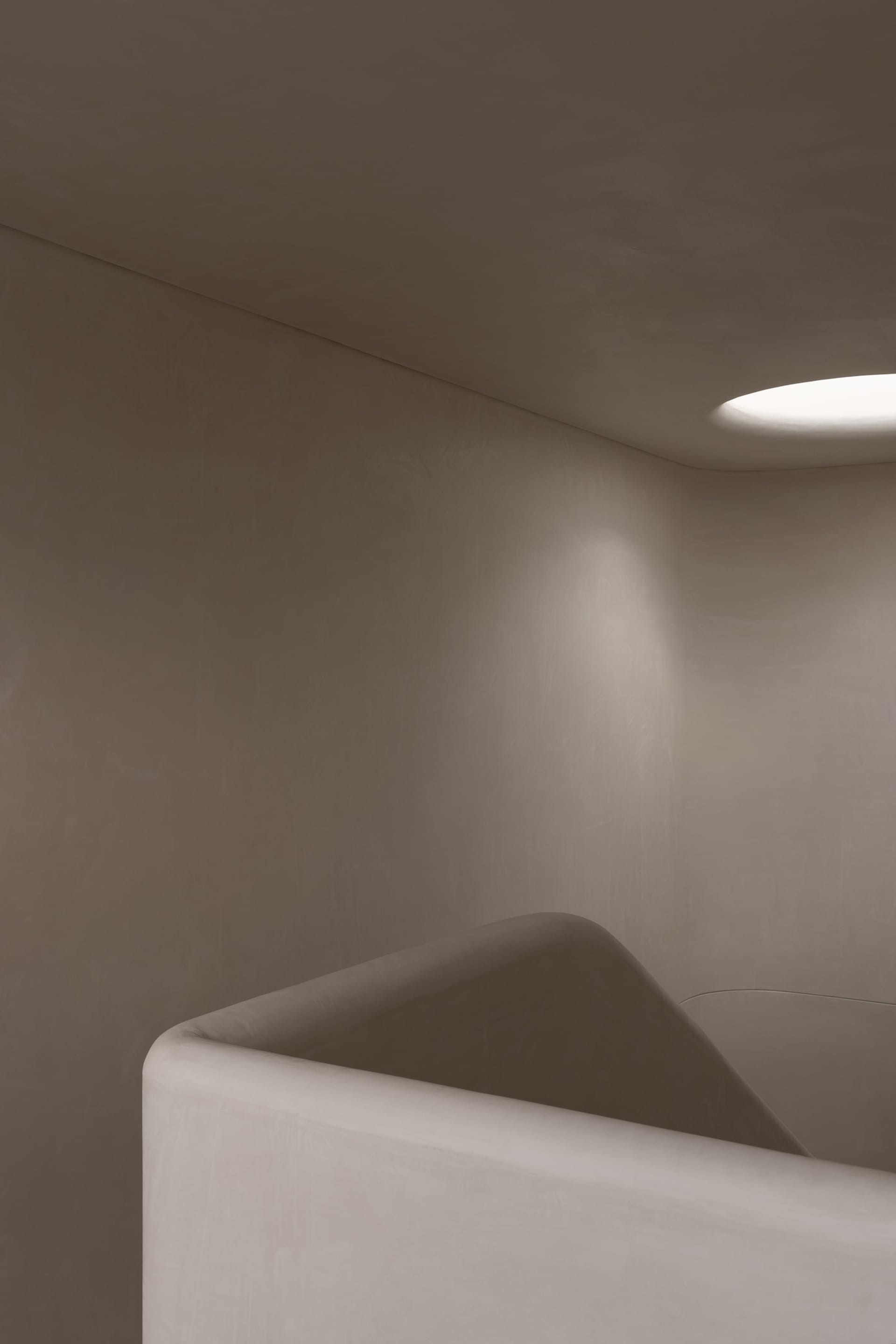 Modern, minimalist concrete staircase with a round light fixture in the ceiling.