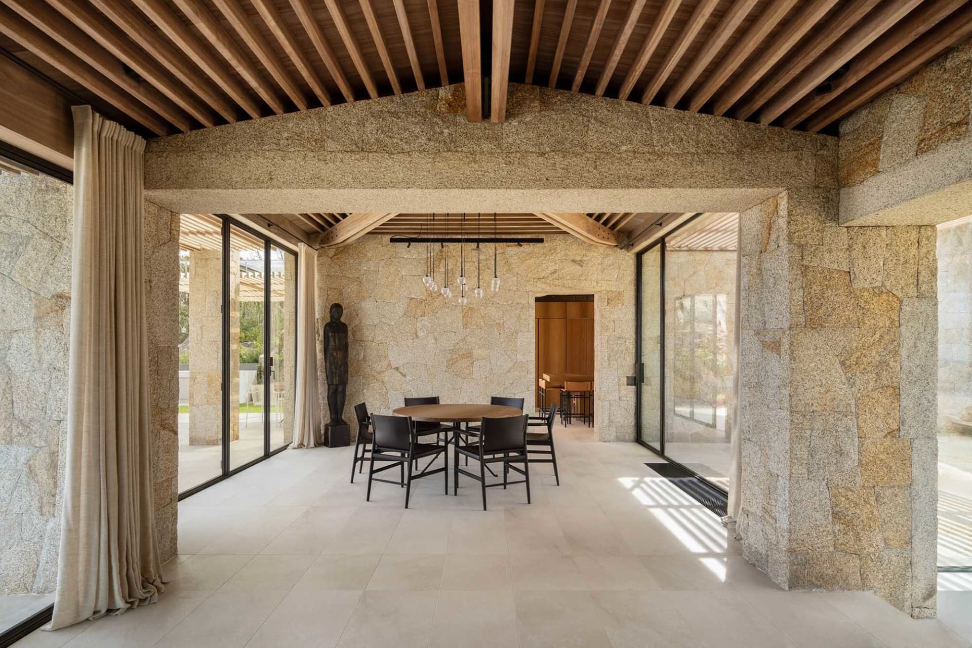 Interior view of a modern, minimalist residential space with stone, wood, and glass materials.
