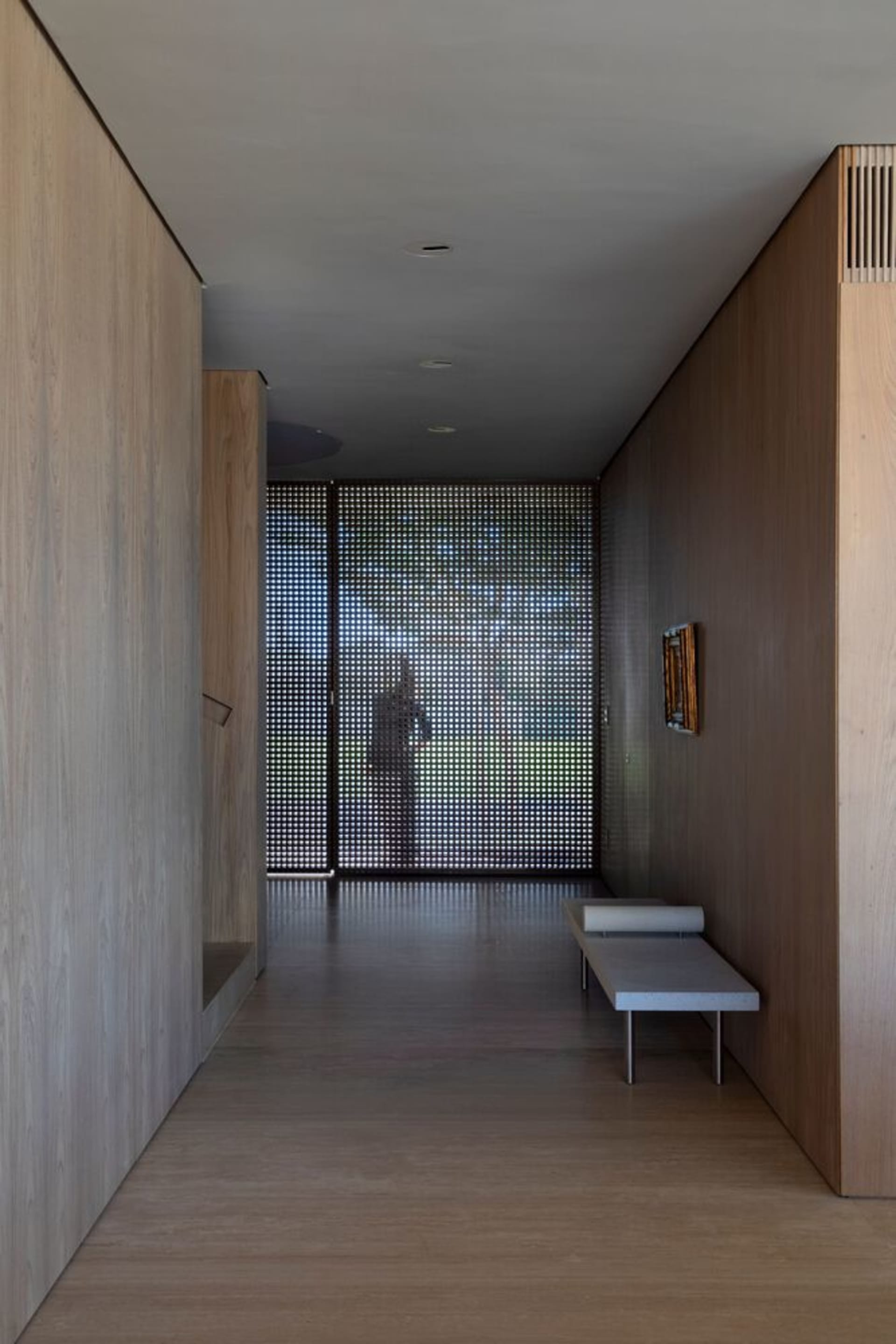 A modern hallway with wood walls and a glass panel at the end.