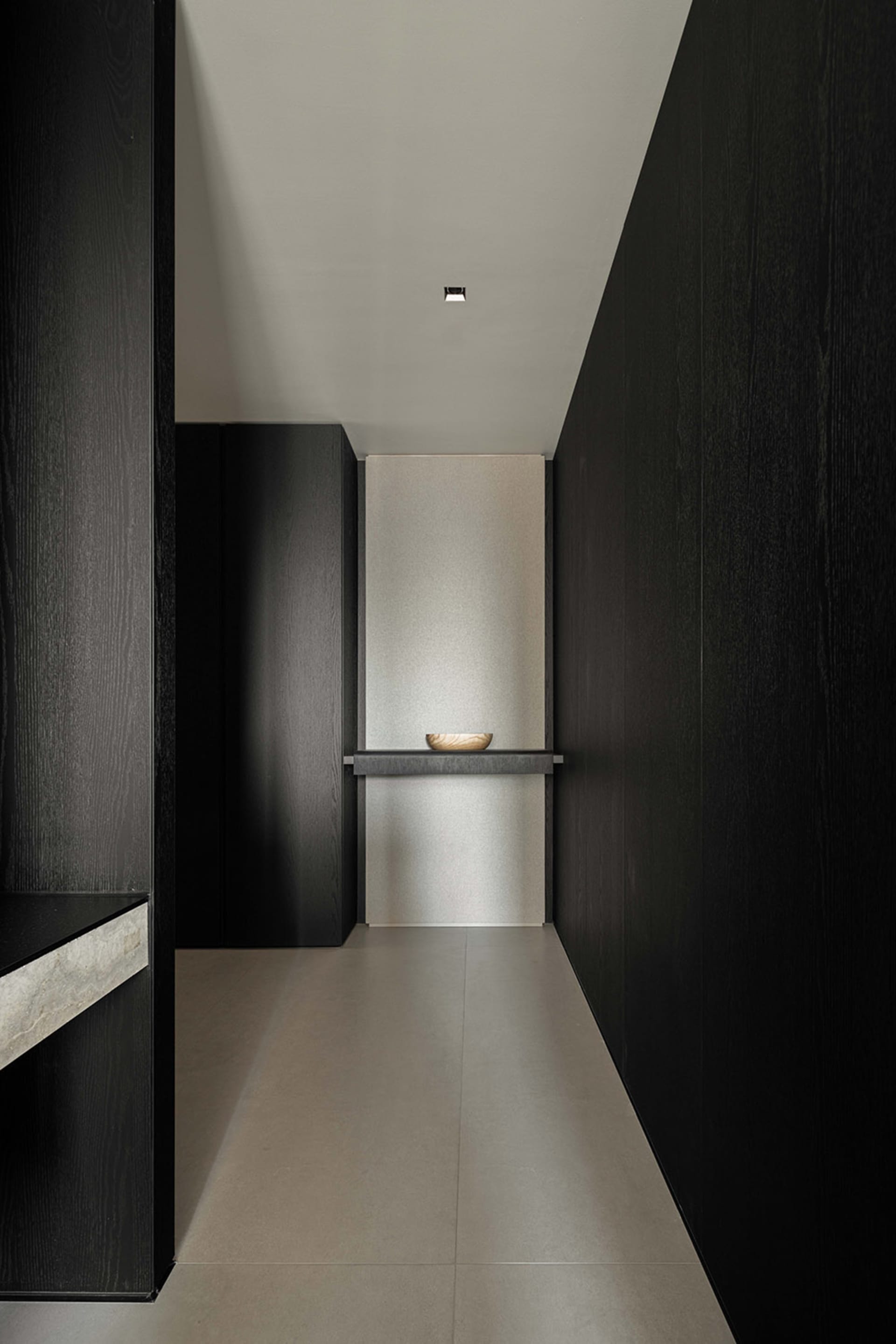 A minimalist room with dark wooden walls and a grey floor