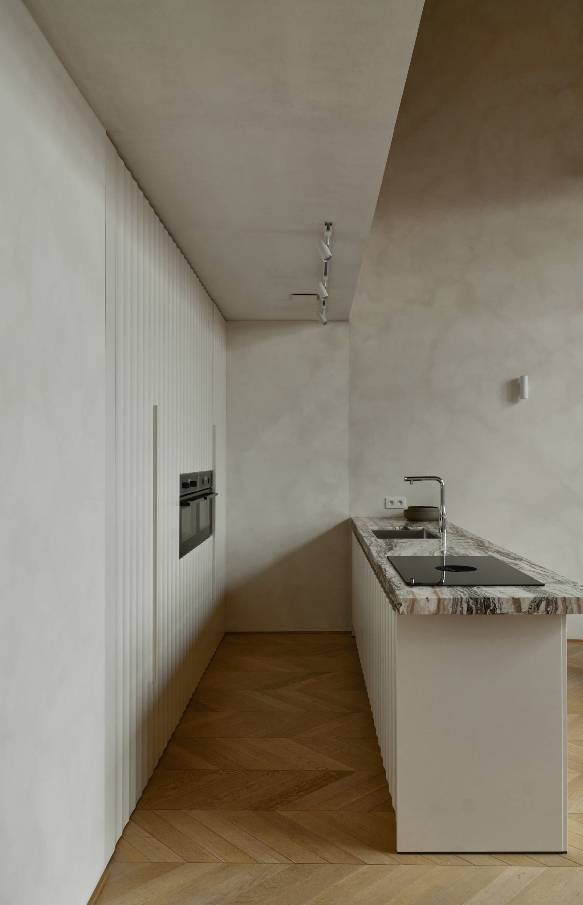 Modern minimalist kitchen featuring a marble countertop and floor-to-ceiling cabinets.