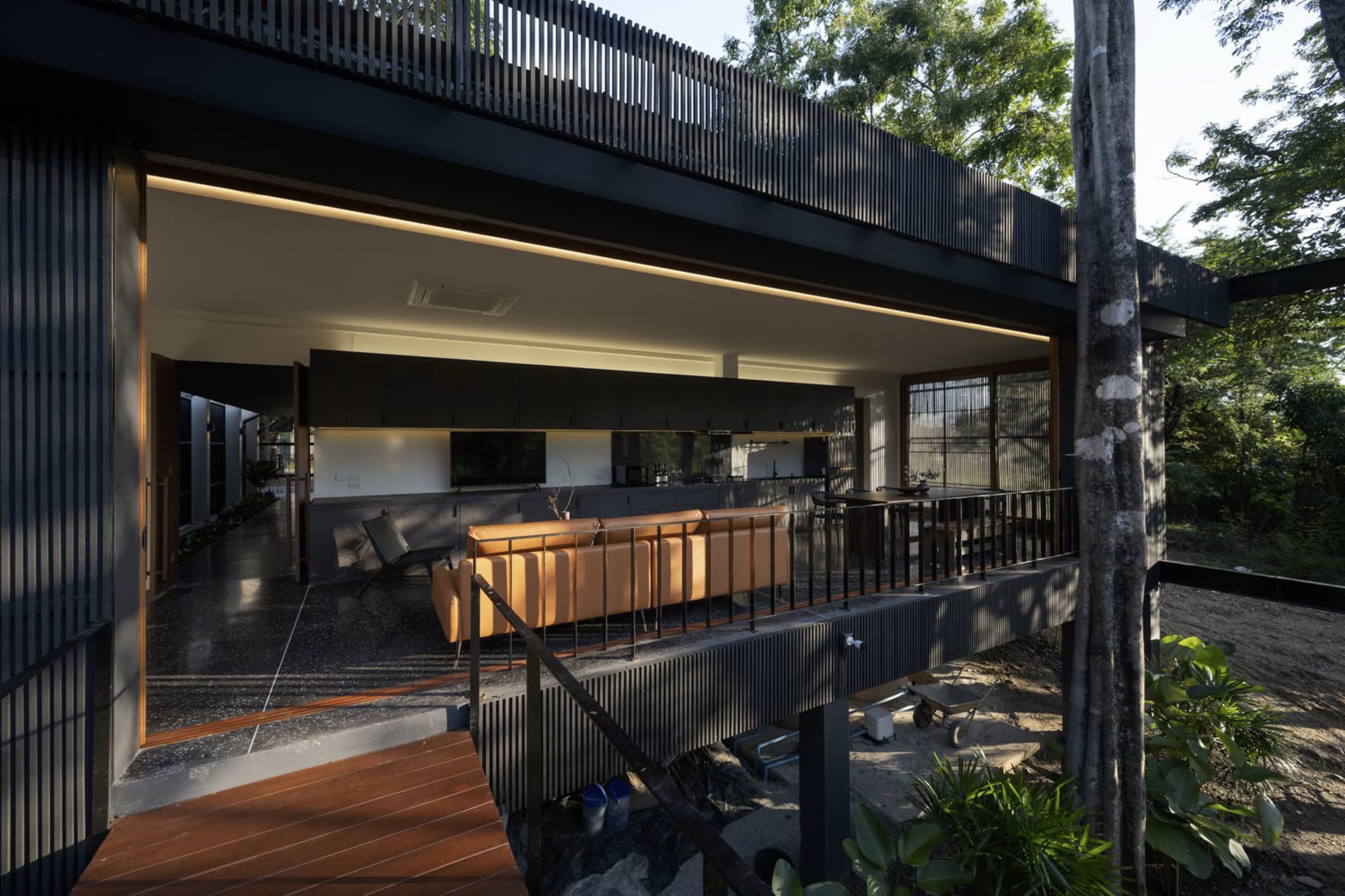 A modern residential outdoor living space featuring wooden flooring, metal railings, and concrete elements.