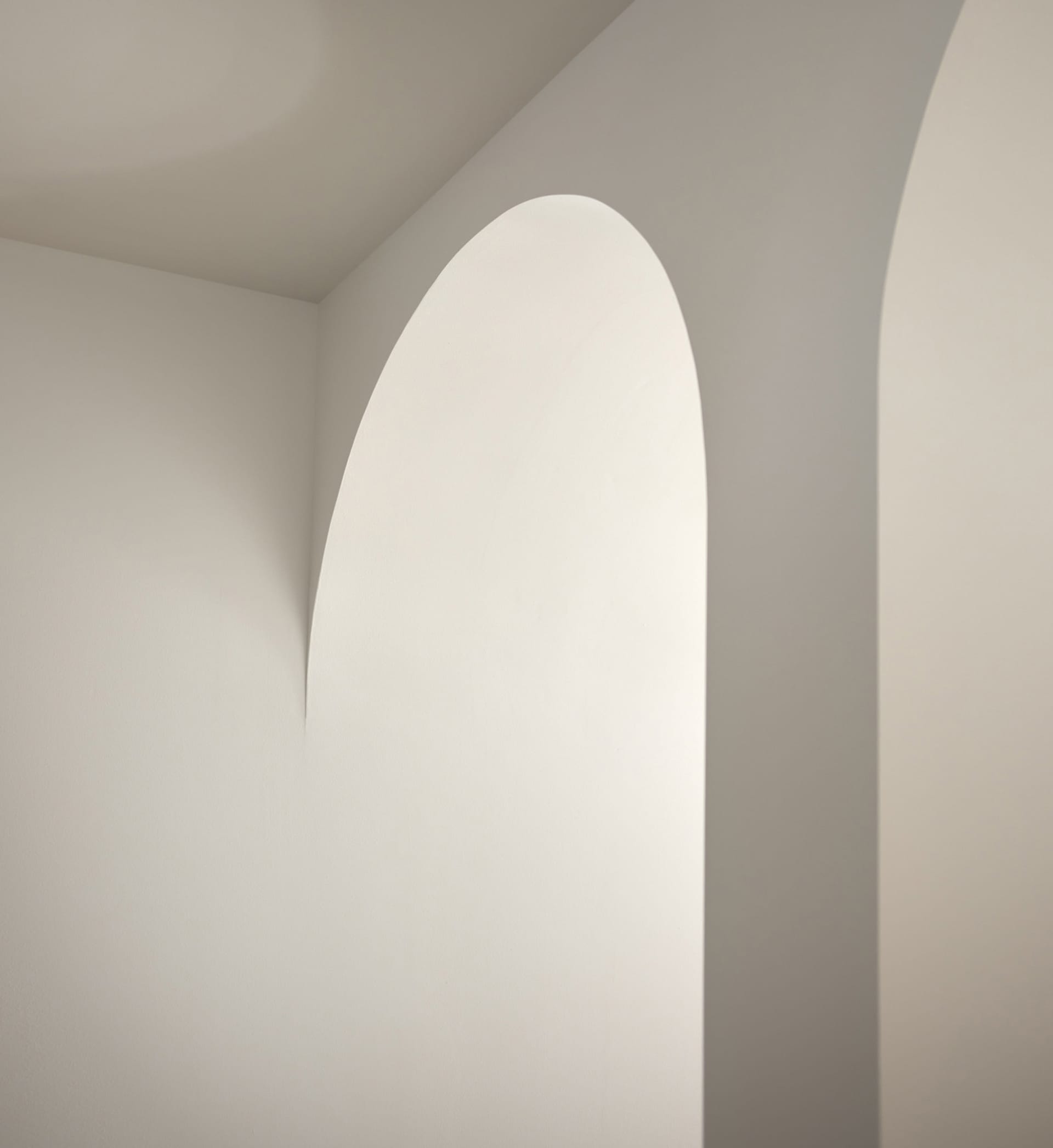 Minimalist white interior with arched doorways and walls.
