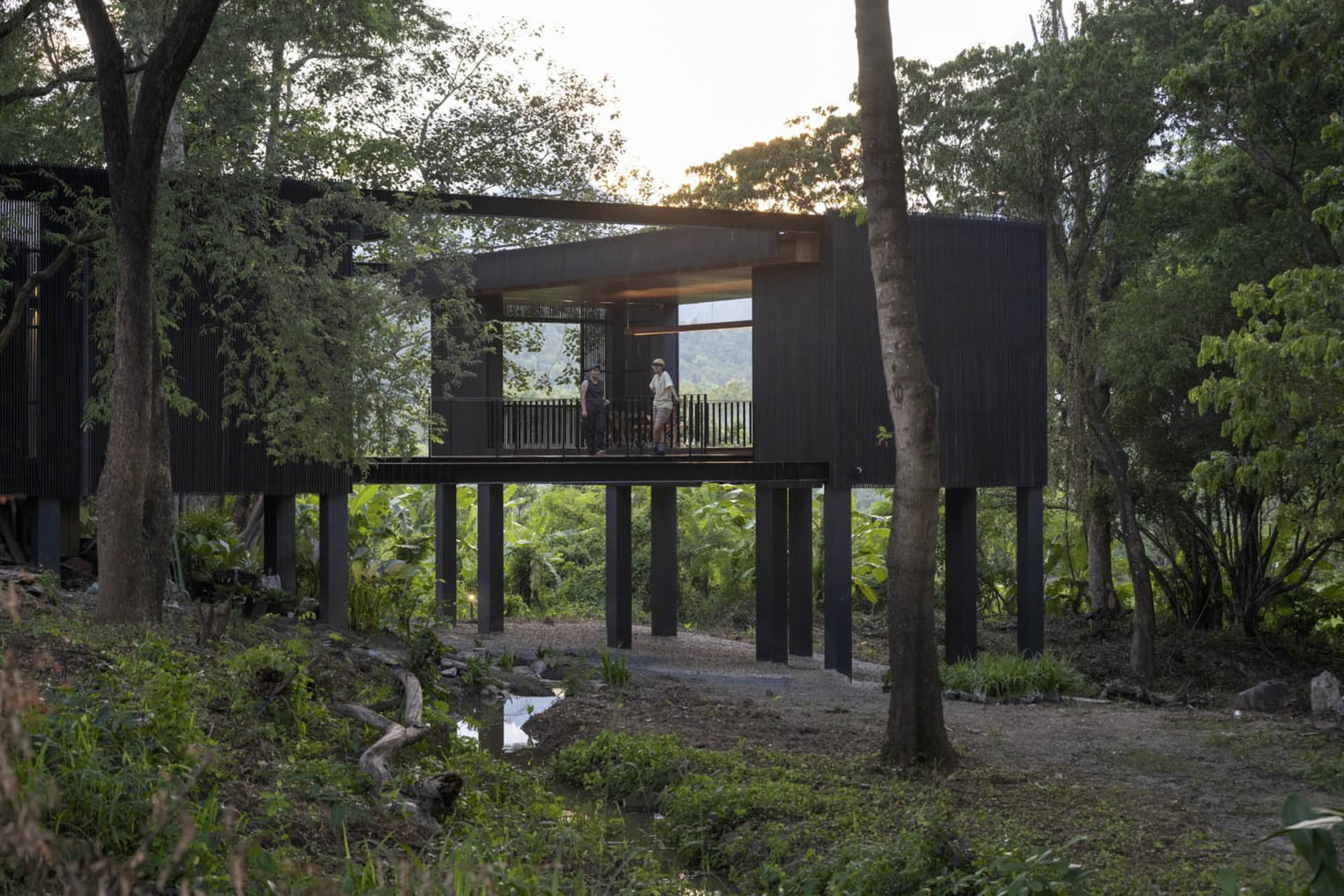 Modern dark wood exterior residential architecture with individuals standing on a veranda.