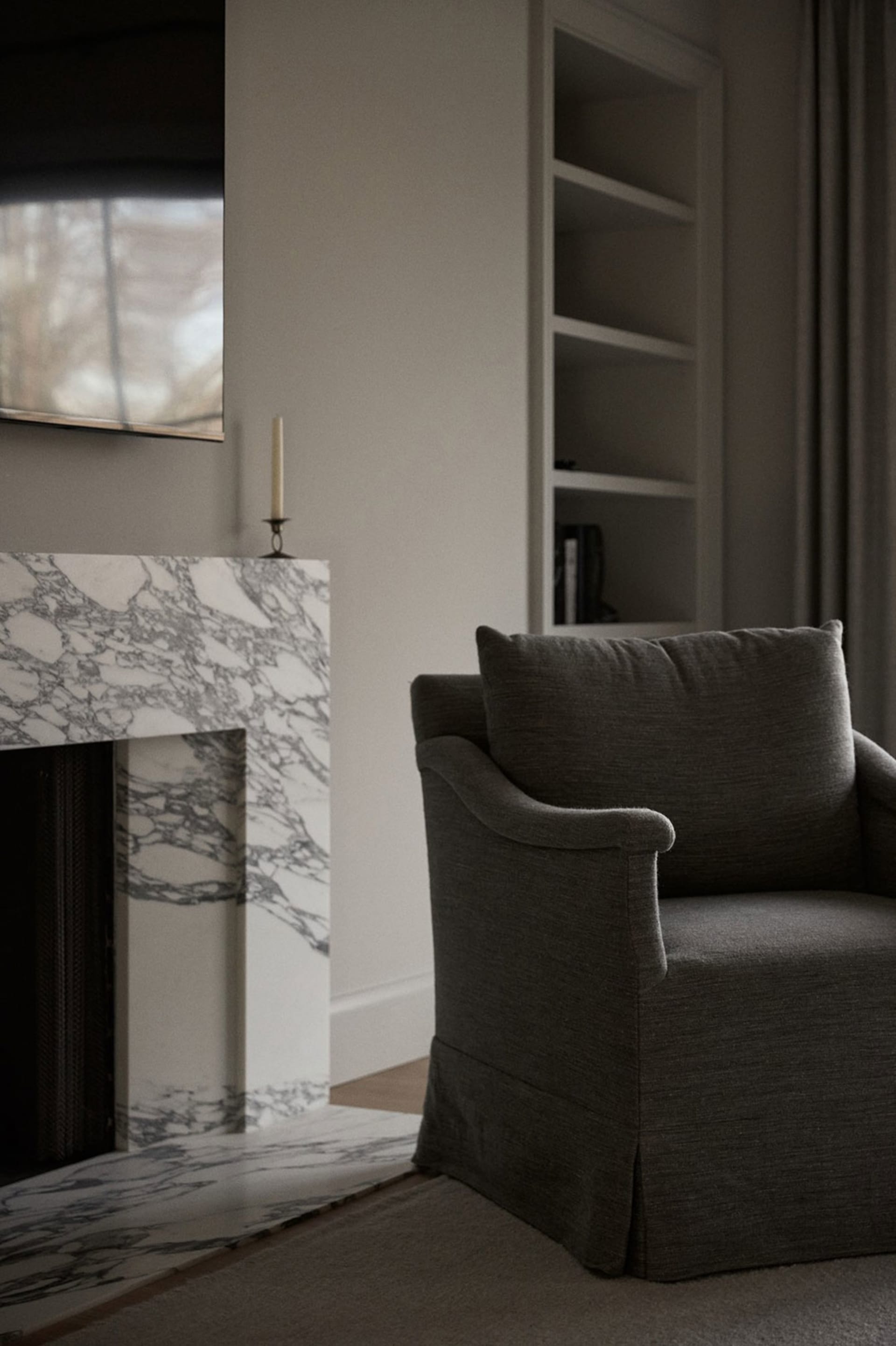 A modern lounge area featuring a marble fireplace and upholstered armchair.