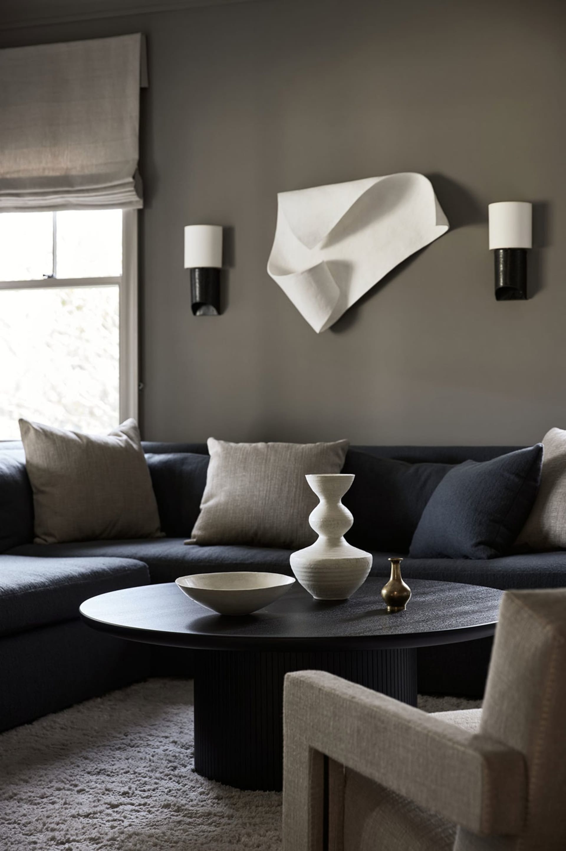 Minimalist living room featuring a textured fabric couch, modern coffee table with decorative vases, and abstract wall art.