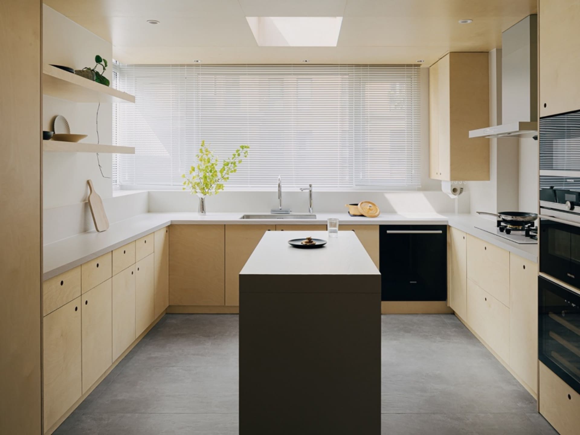 Modern minimalist kitchen with white countertops and wooden cabinetry.