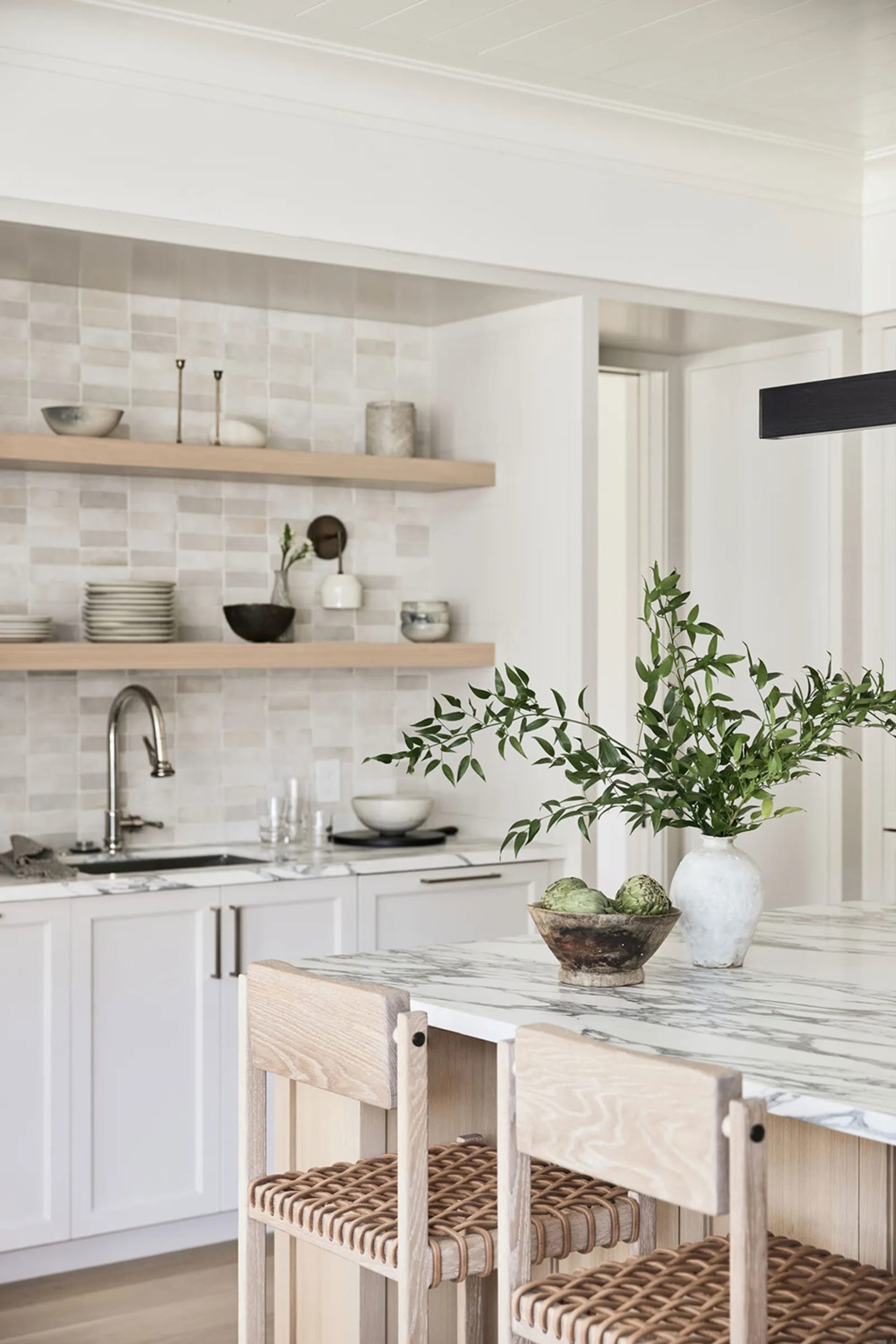 Modern, minimalist kitchen with white cabinets, marble countertops, and wooden accents.