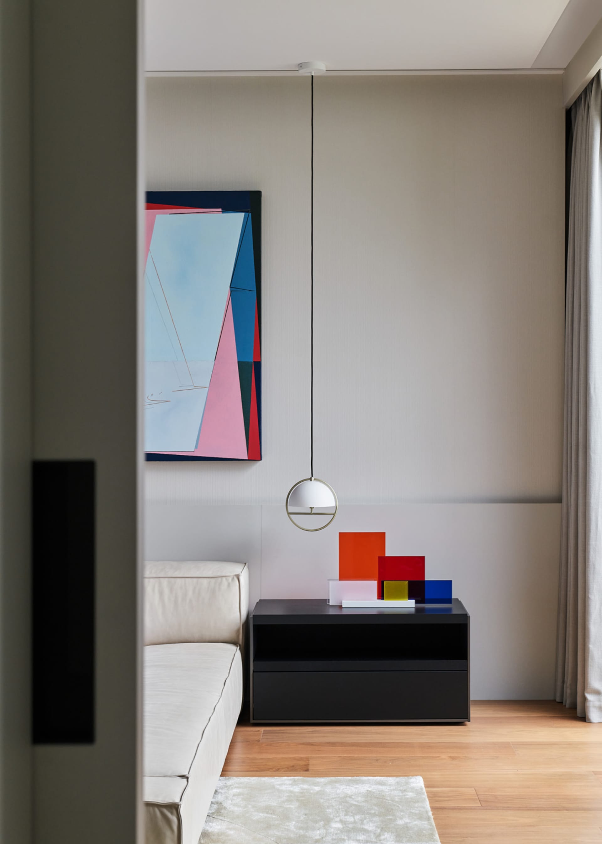 Modern living room with minimalist decor and a geometric abstract painting.