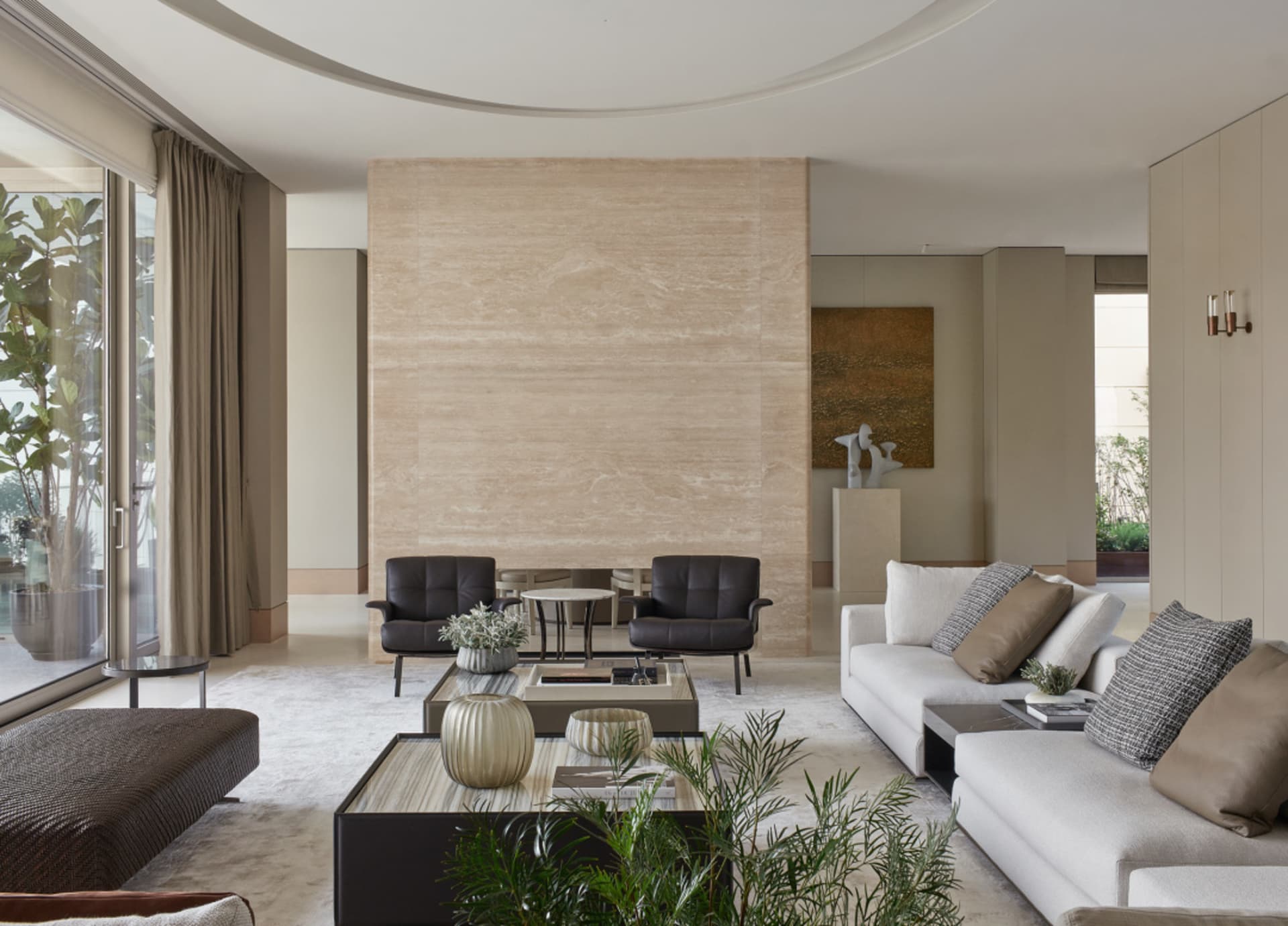A modern living room featuring a marble wall, white sofa, and black chairs.
