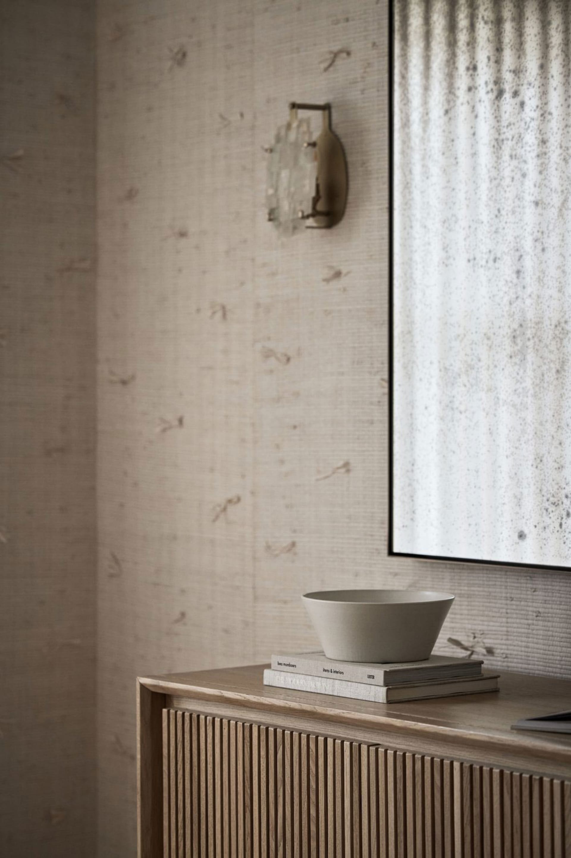 A modern minimalist bedroom featuring a wooden sideboard with a matte surface.