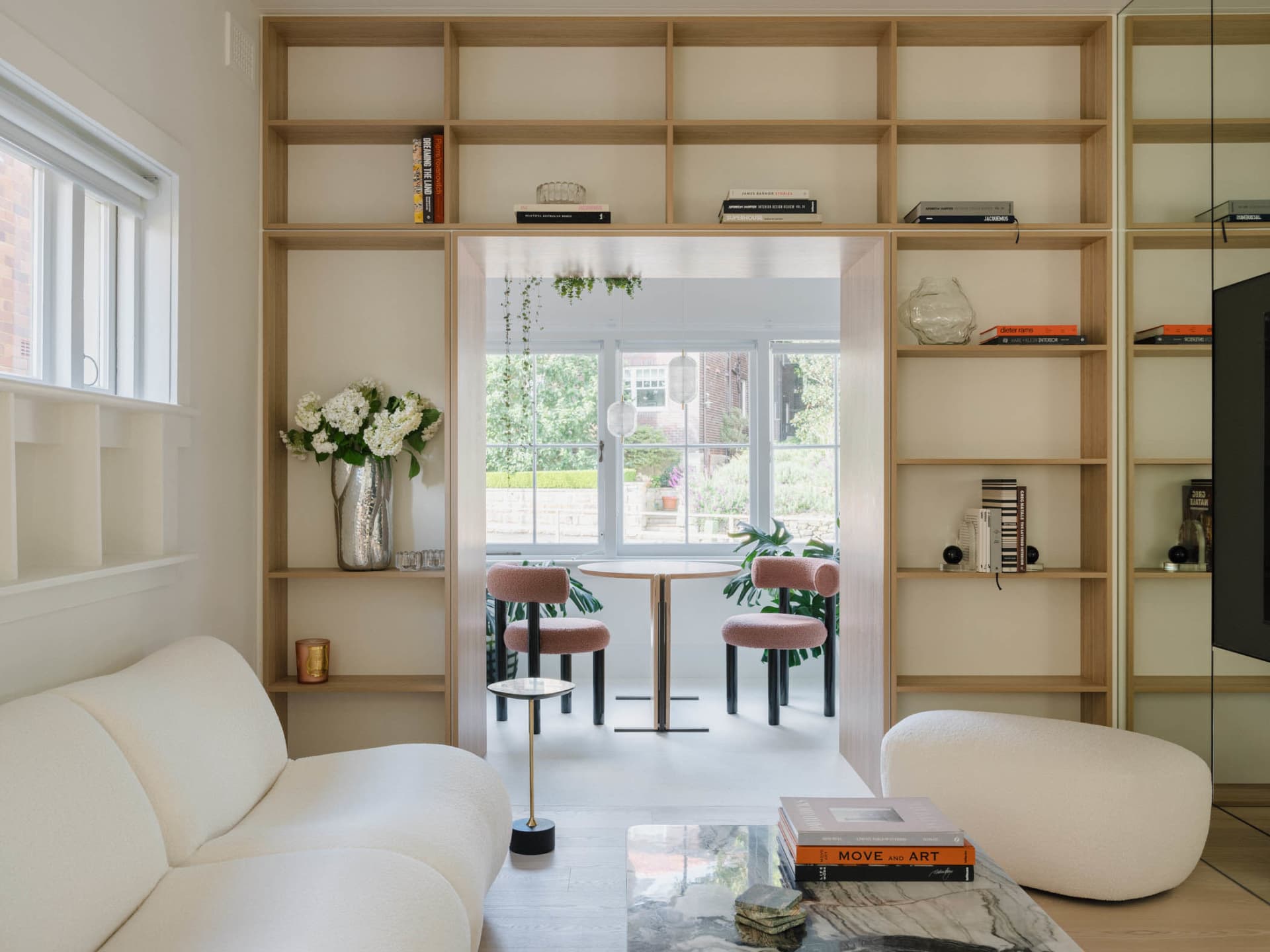 Modern living room featuring white furniture and wooden shelves.
