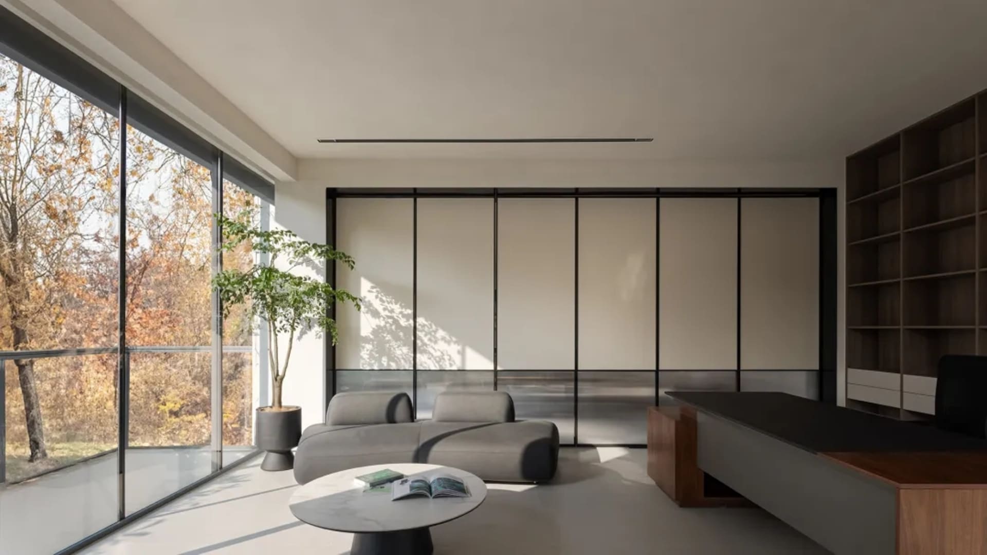 A modern office space featuring a sleek glass panel system and contemporary furniture.