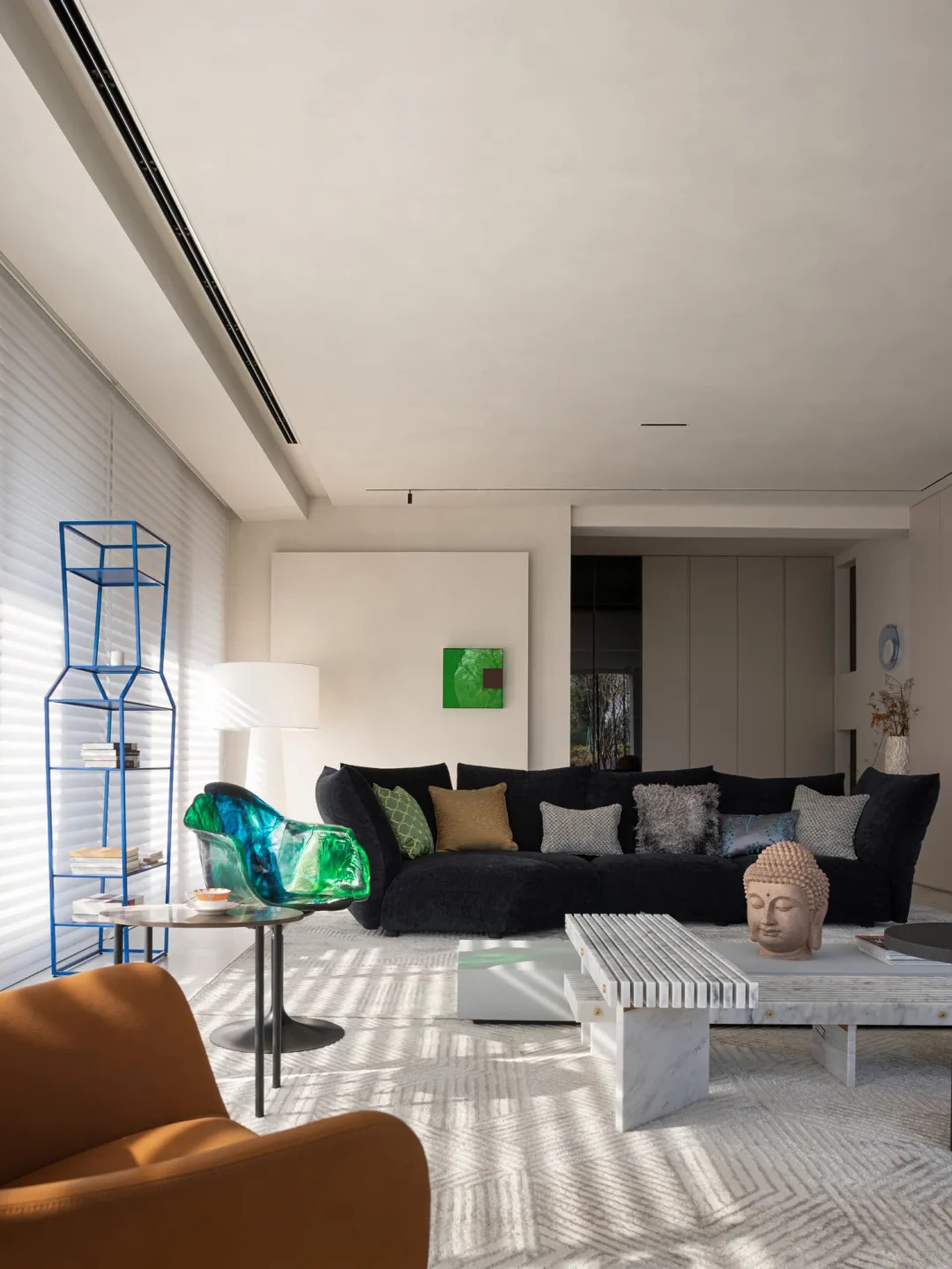 Modern living room with a black sofa, green and brown pillows, and a blue wire shelving unit.
