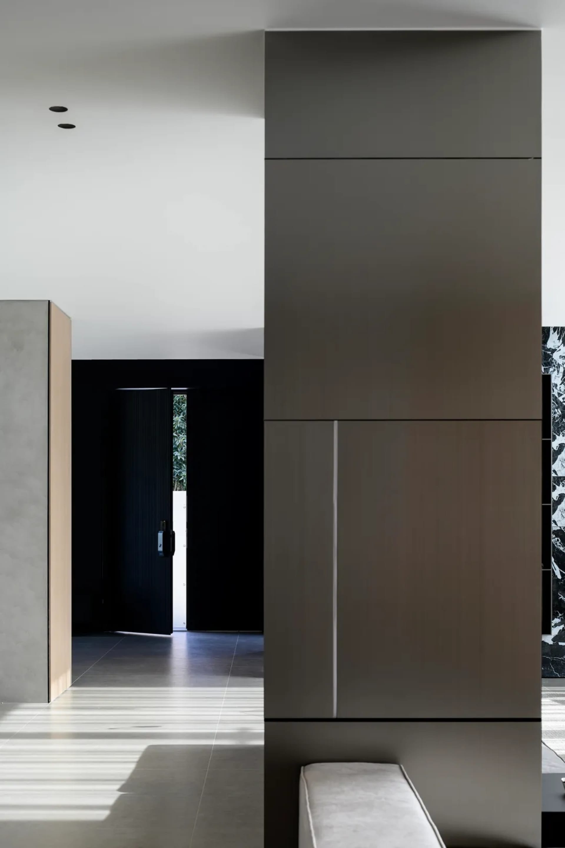 A minimalist, modern interior space with concrete walls, dark accents, and natural light coming through a window with a view