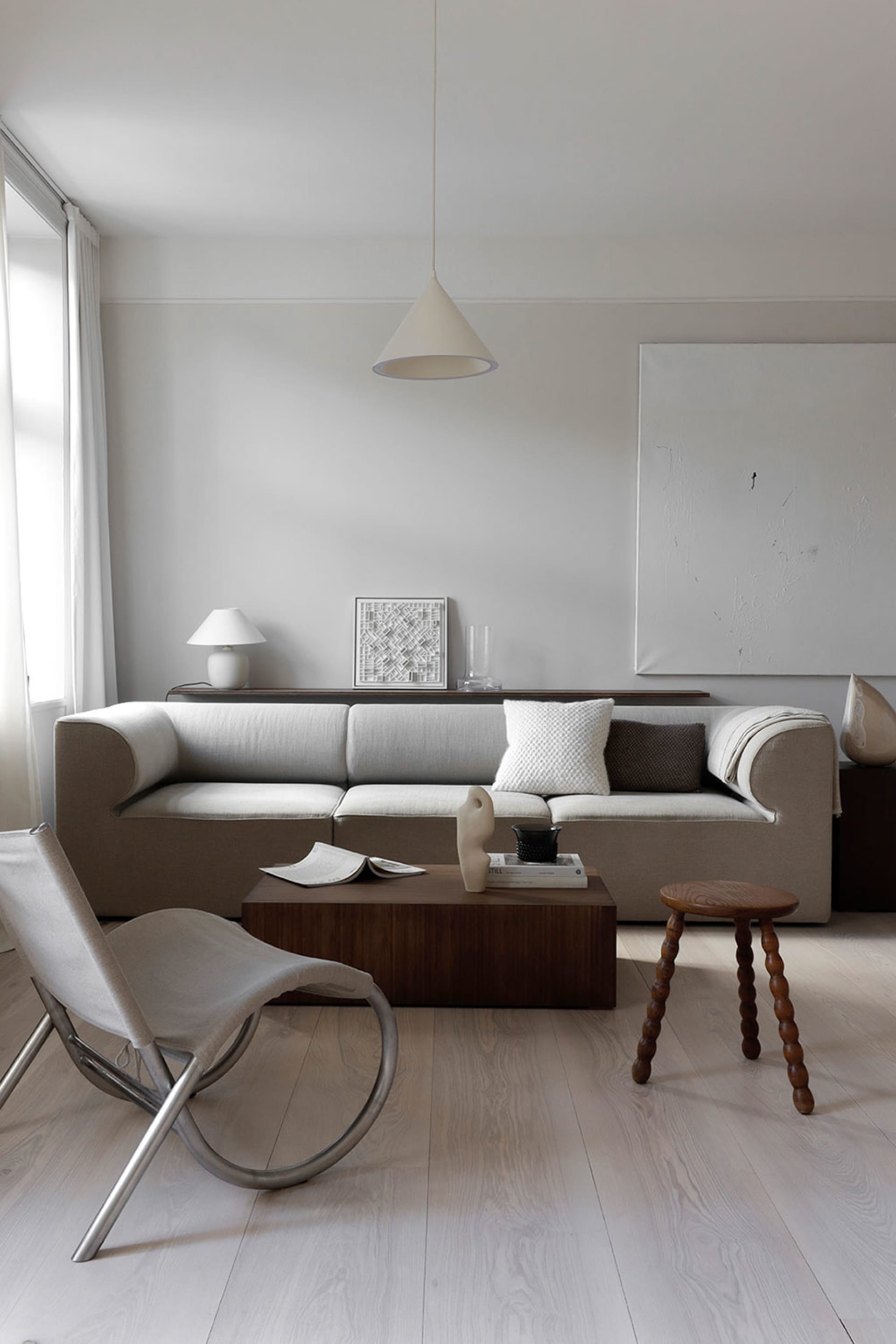 A minimalist living room with fabric sofa, wooden coffee table, and metallic chair.