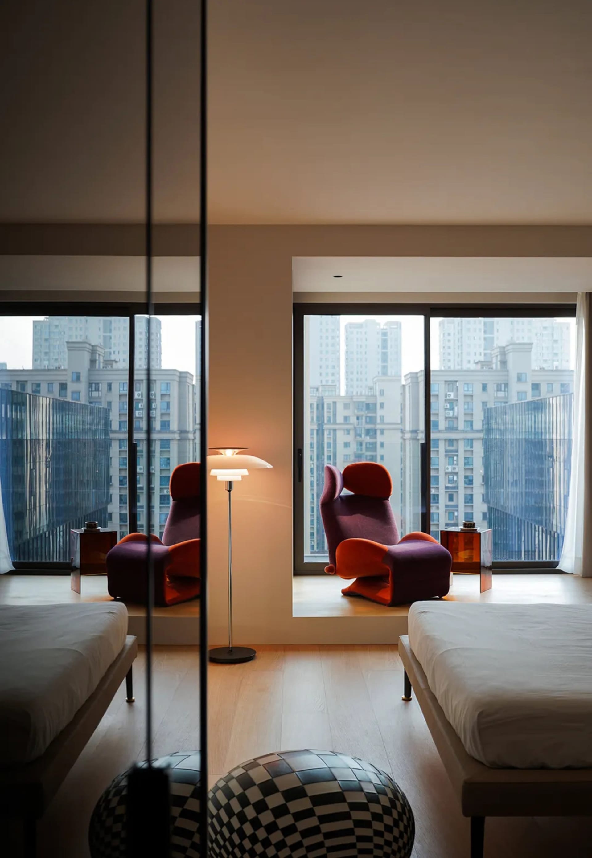 A modern bedroom featuring wooden furniture, white floor, and a large window with a cityscape view.