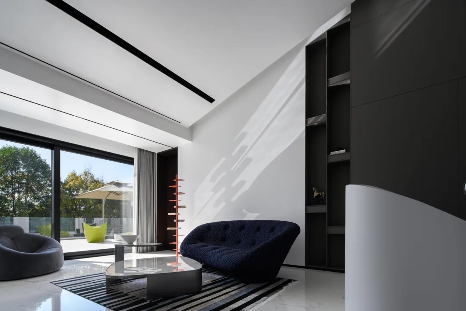 Modern living room with concrete and glass materials, featuring a cozy navy couch, a minimalist glass table, and a sleek, mod
