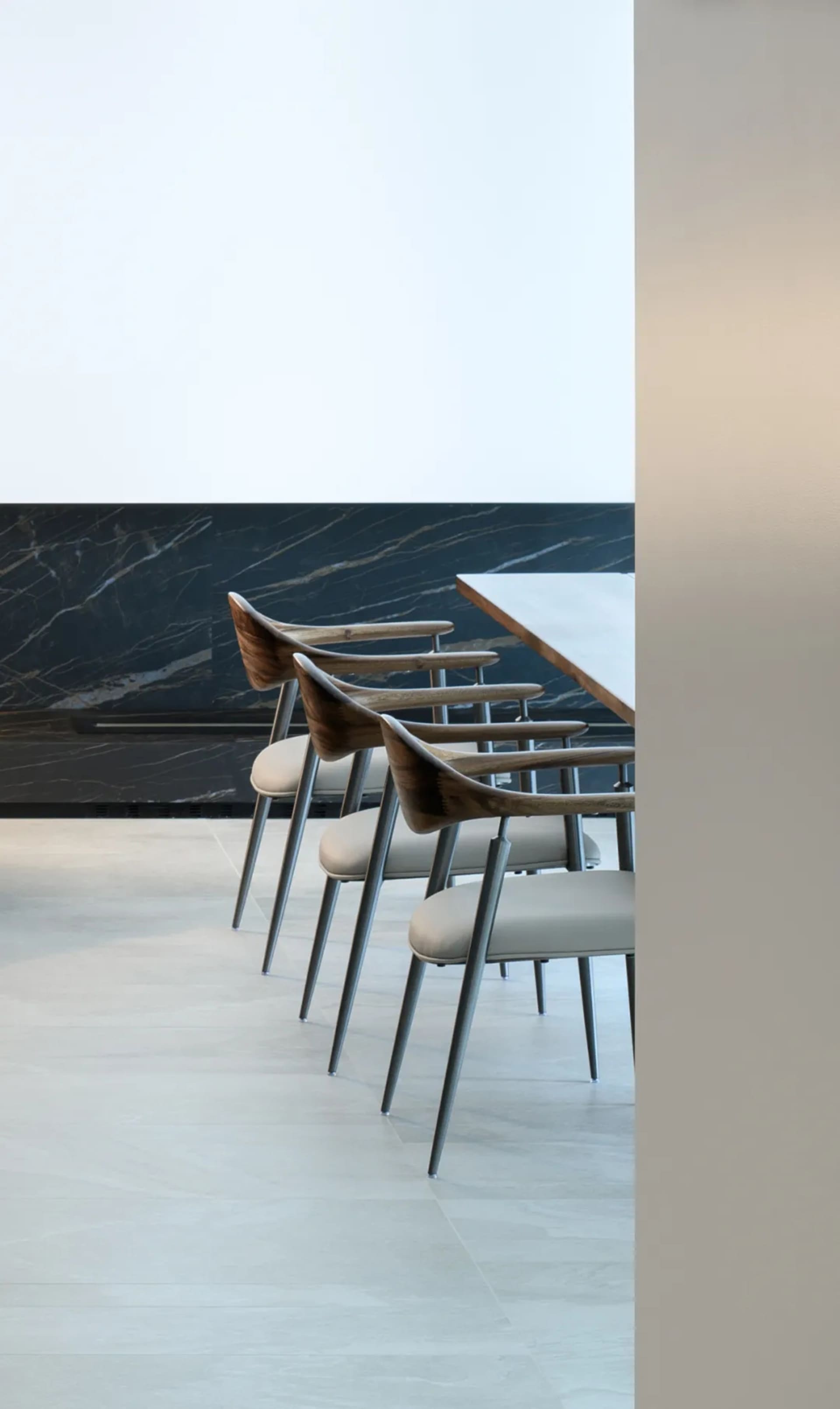 Modern interior design featuring wooden chairs with leather seats and metal legs.