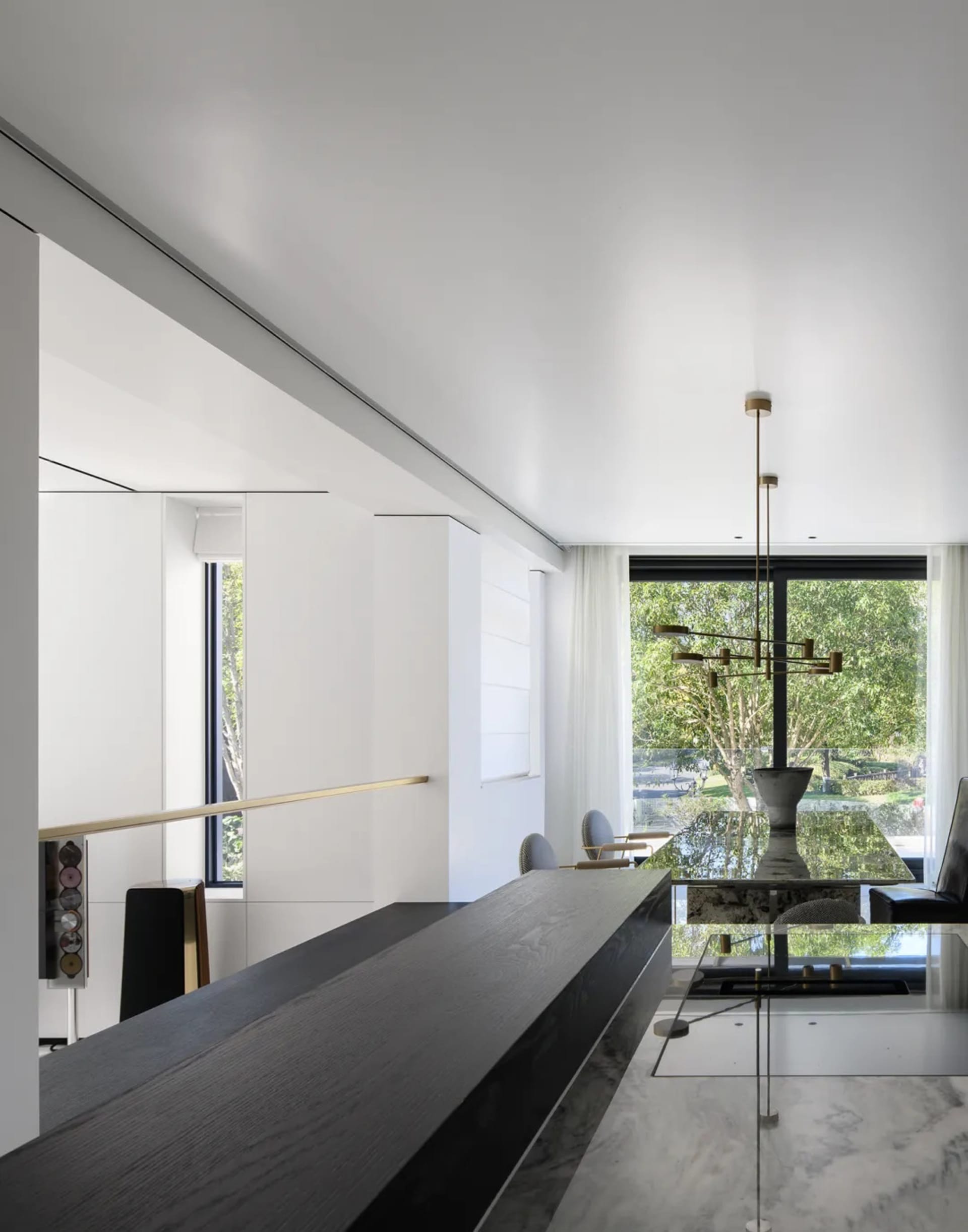 A modern living space featuring a minimalist interior with white walls and mixed materials, including a black dining table se