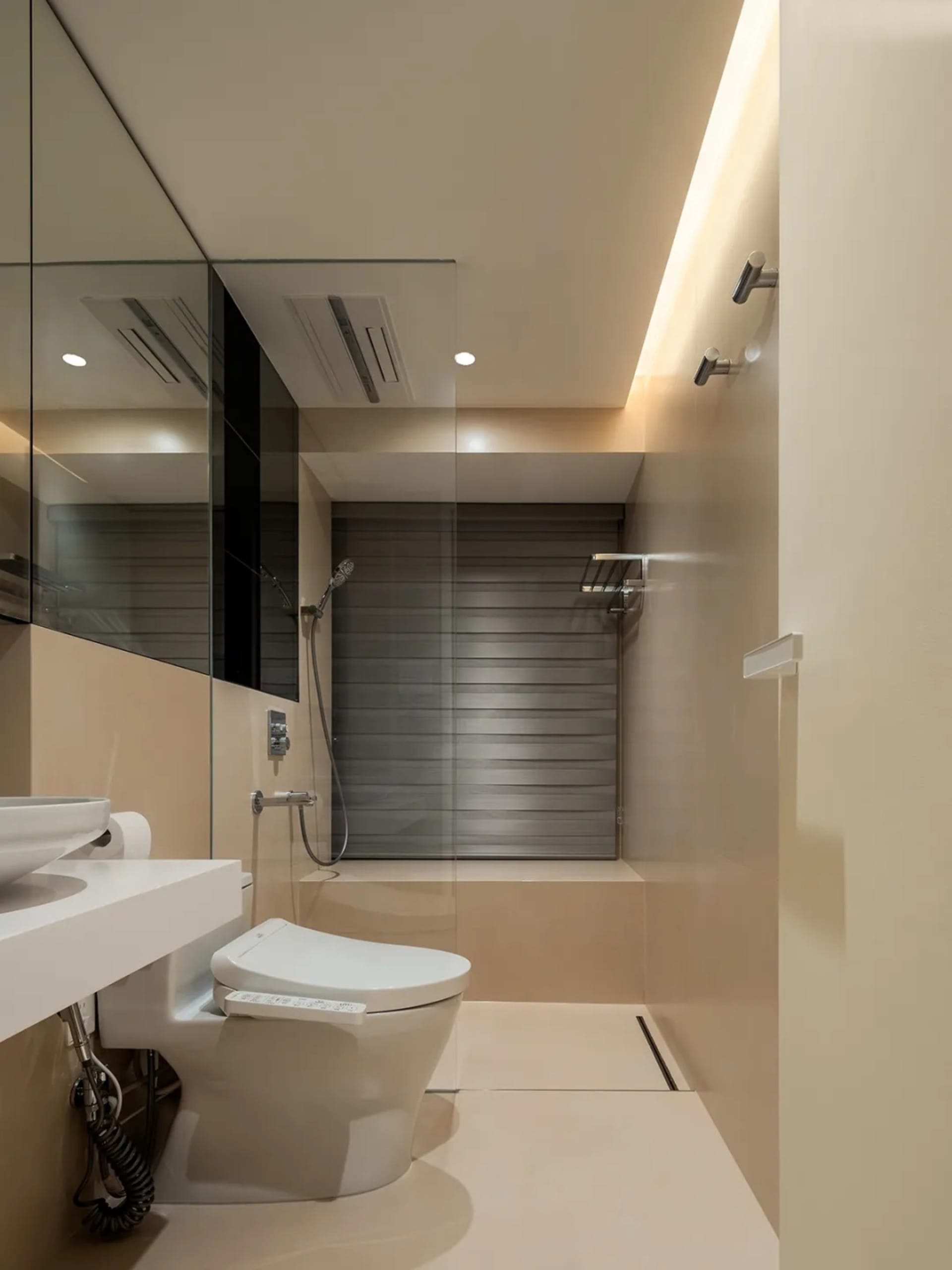 Modern bathroom with white fixtures, beige walls, and a walk-in shower.
