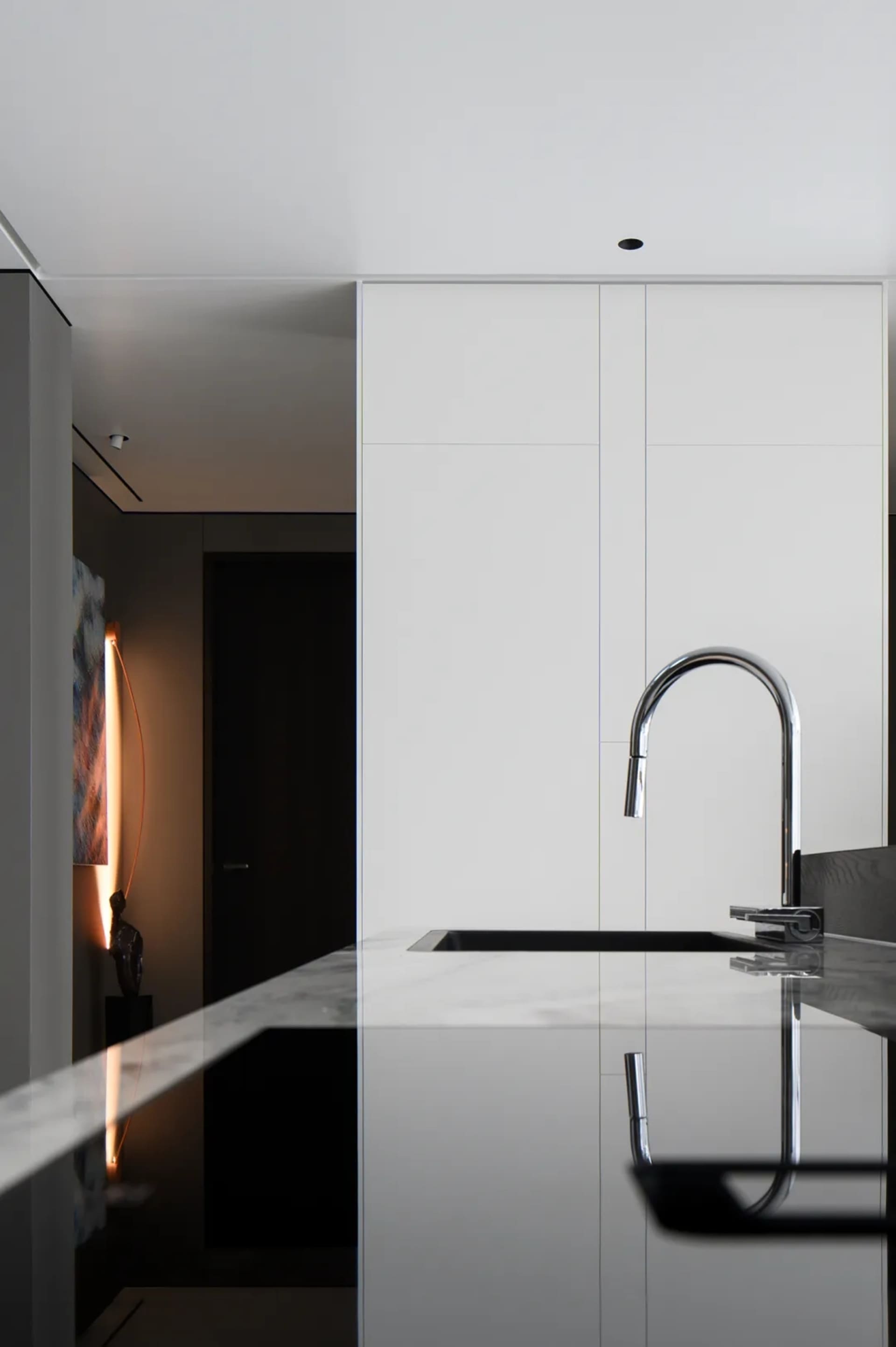 Modern minimalist kitchen with a marble countertop and stainless steel faucet.