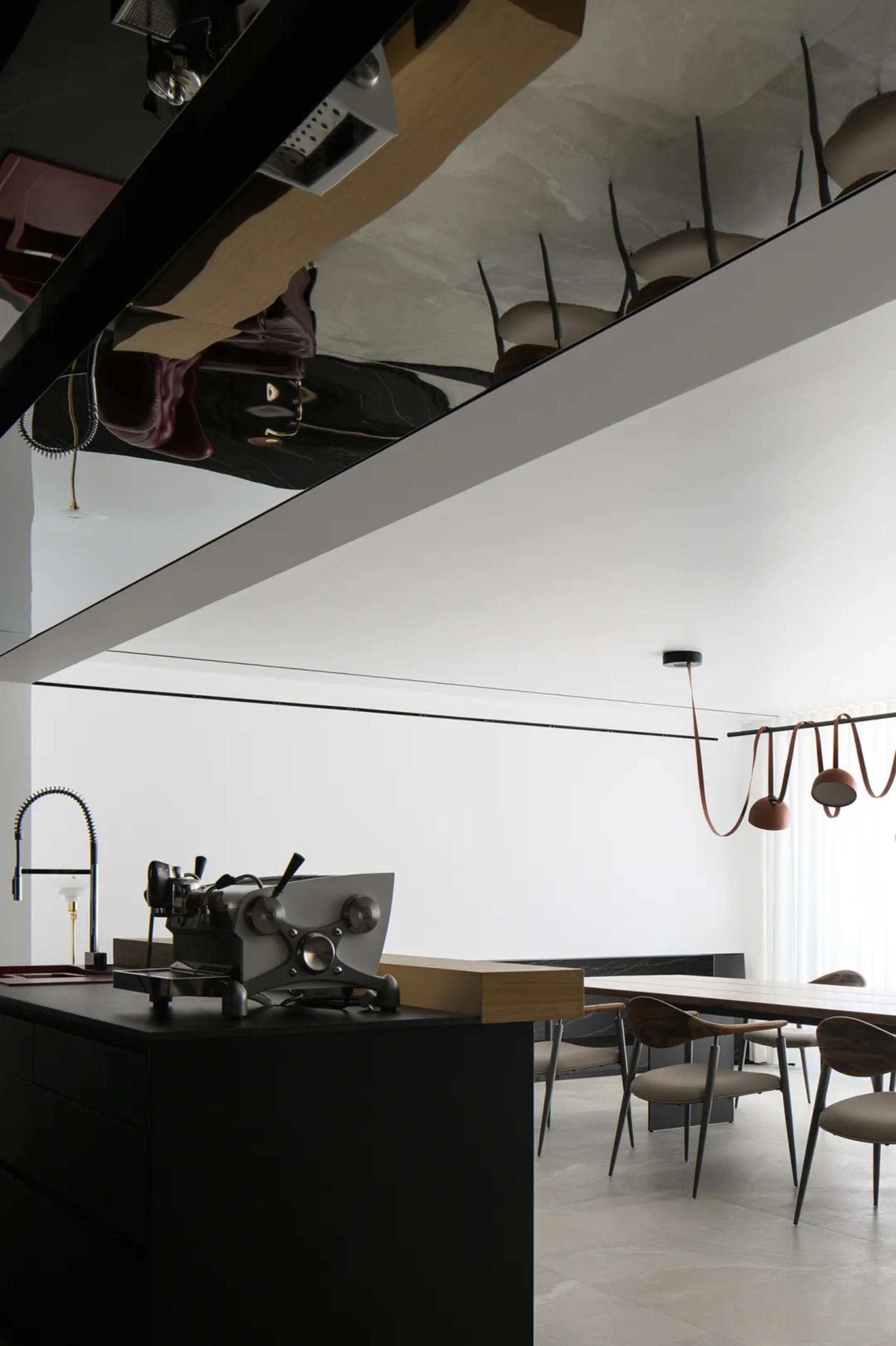 Modern kitchen and dining space featuring metallic black cabinetry, wood accents, and minimalist design.