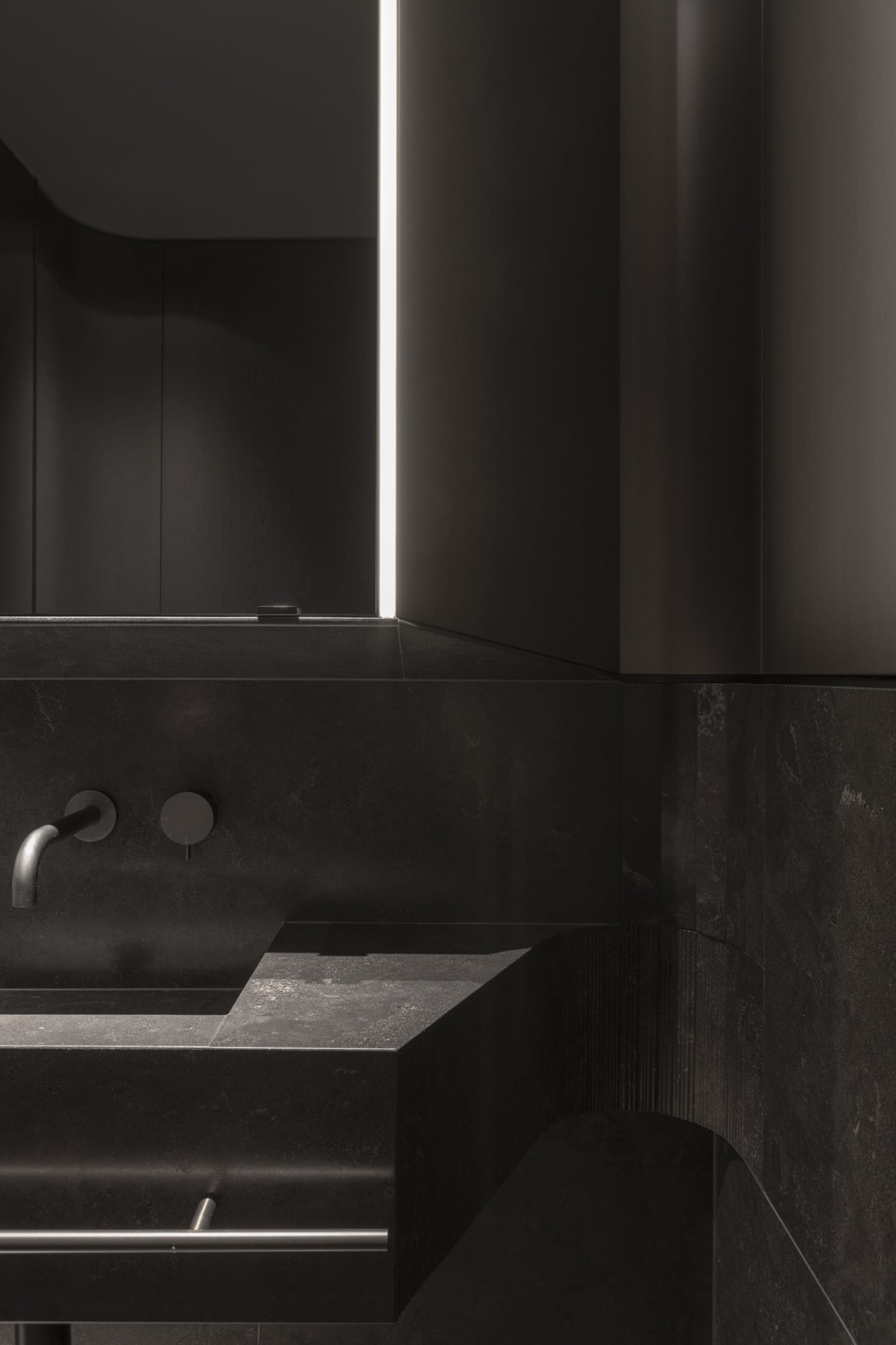 A modern bathroom with black marble surfaces and minimalist design.