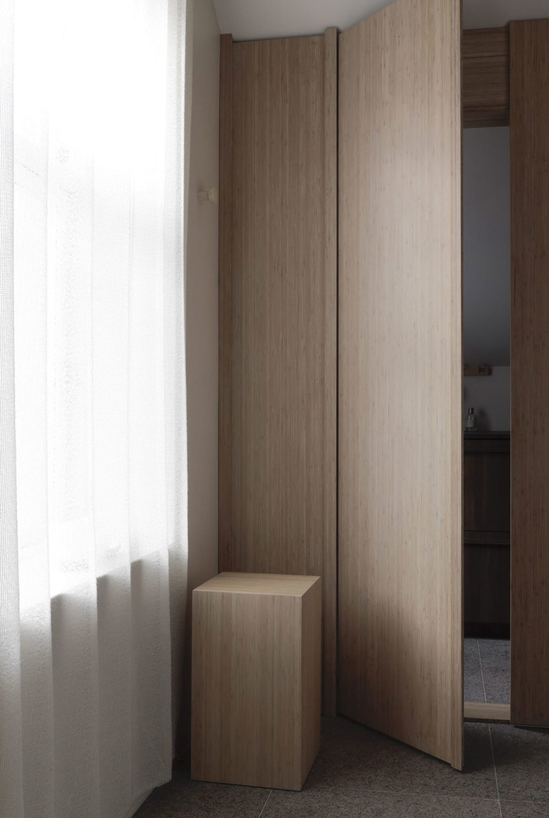 A modern closet with wooden folding doors, open to reveal a minimalist interior.