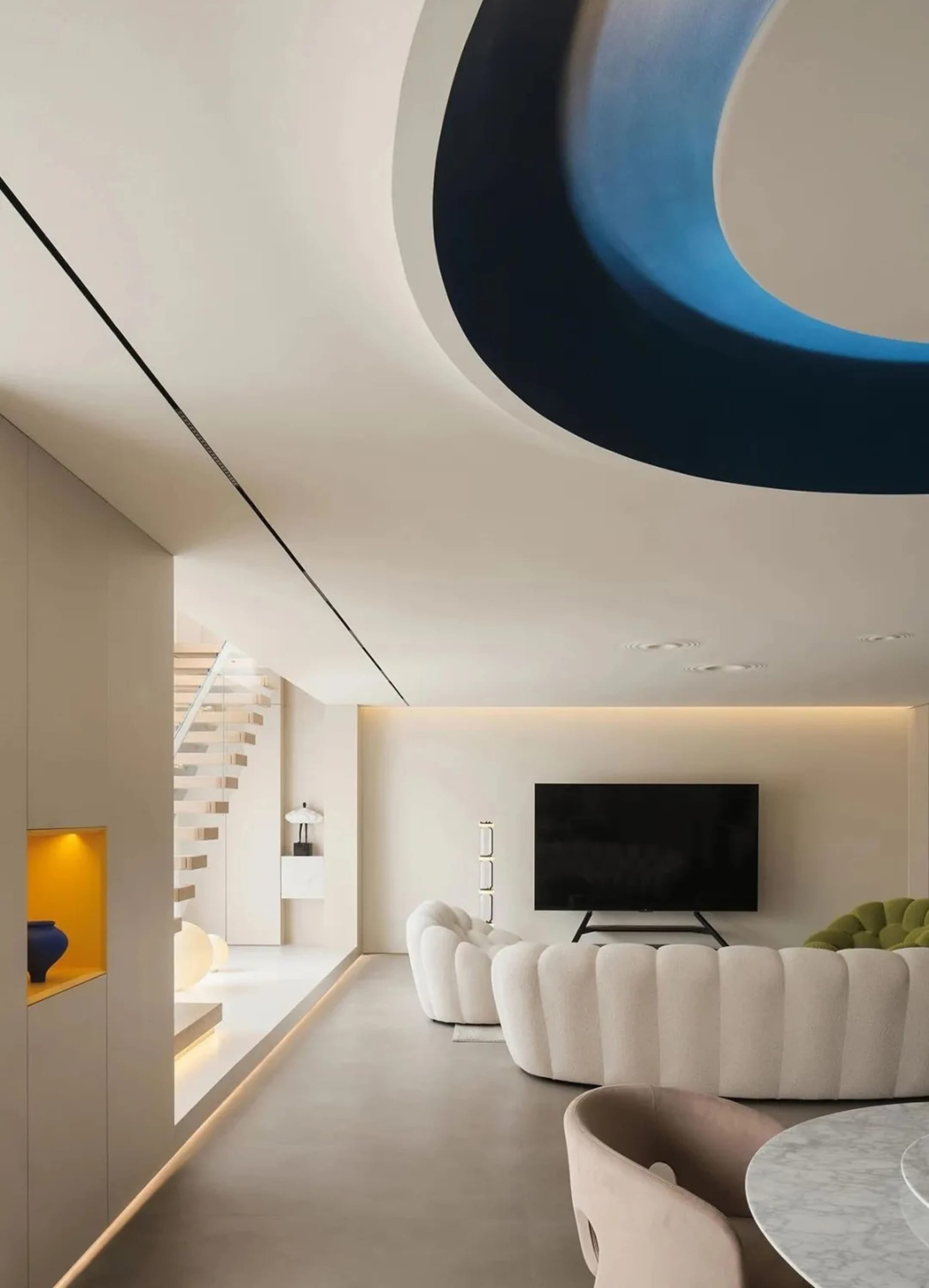 A modern living room with a curvilinear blue ceiling feature and concrete floor.