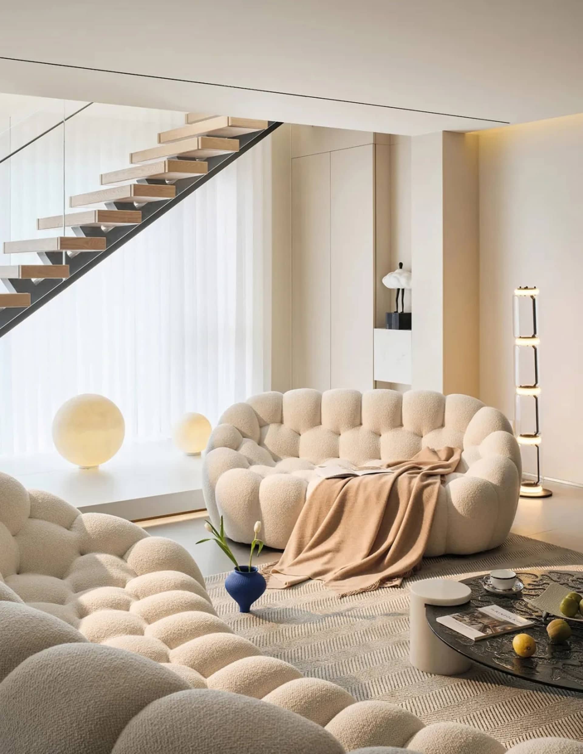 Modern living room with a white, plush, bubble-like sofa, a round coffee table, and a floor lamp in a contemporary interior d