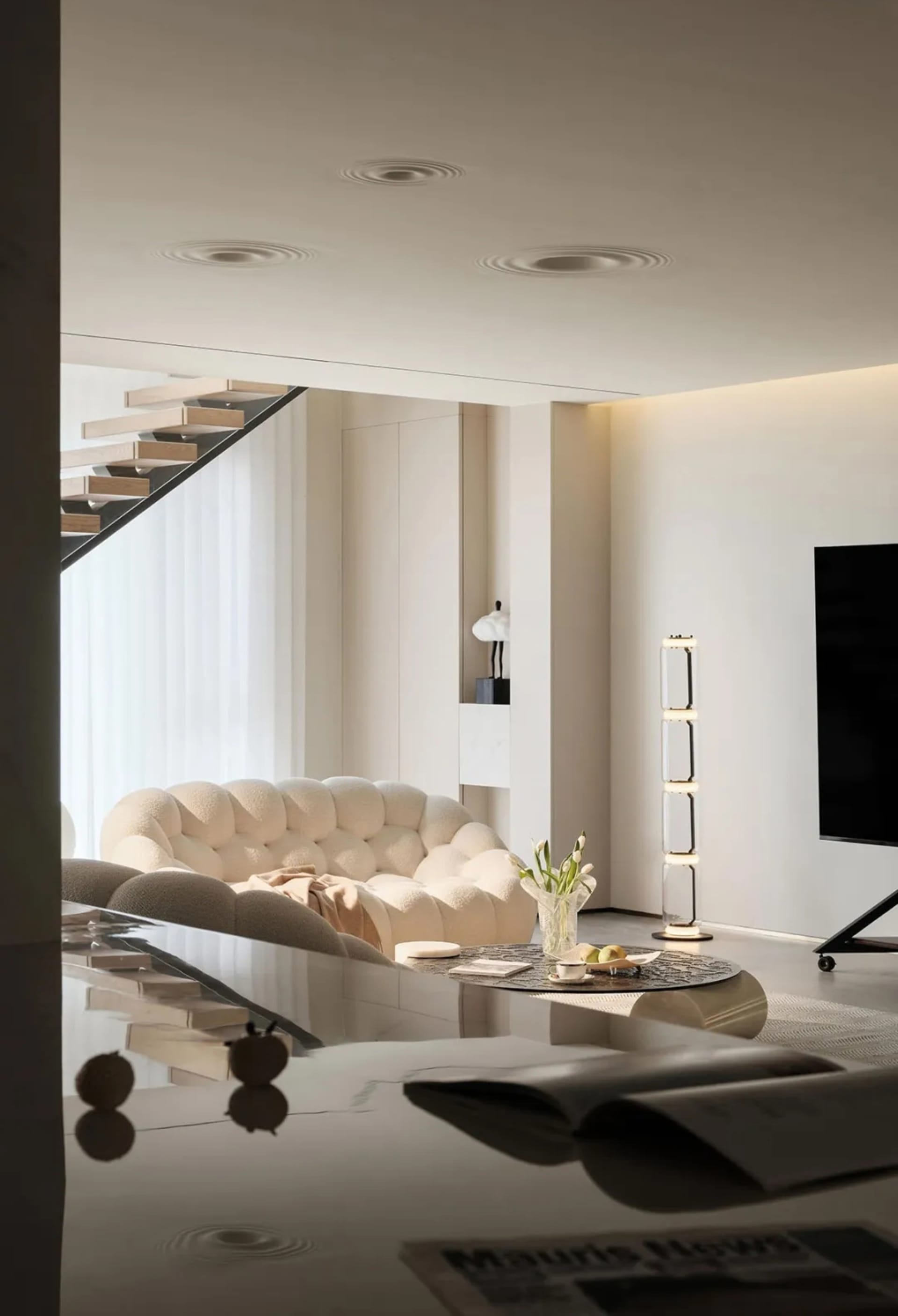 Modern minimalist living room featuring a white rug, furniture, and shelves with lighting.