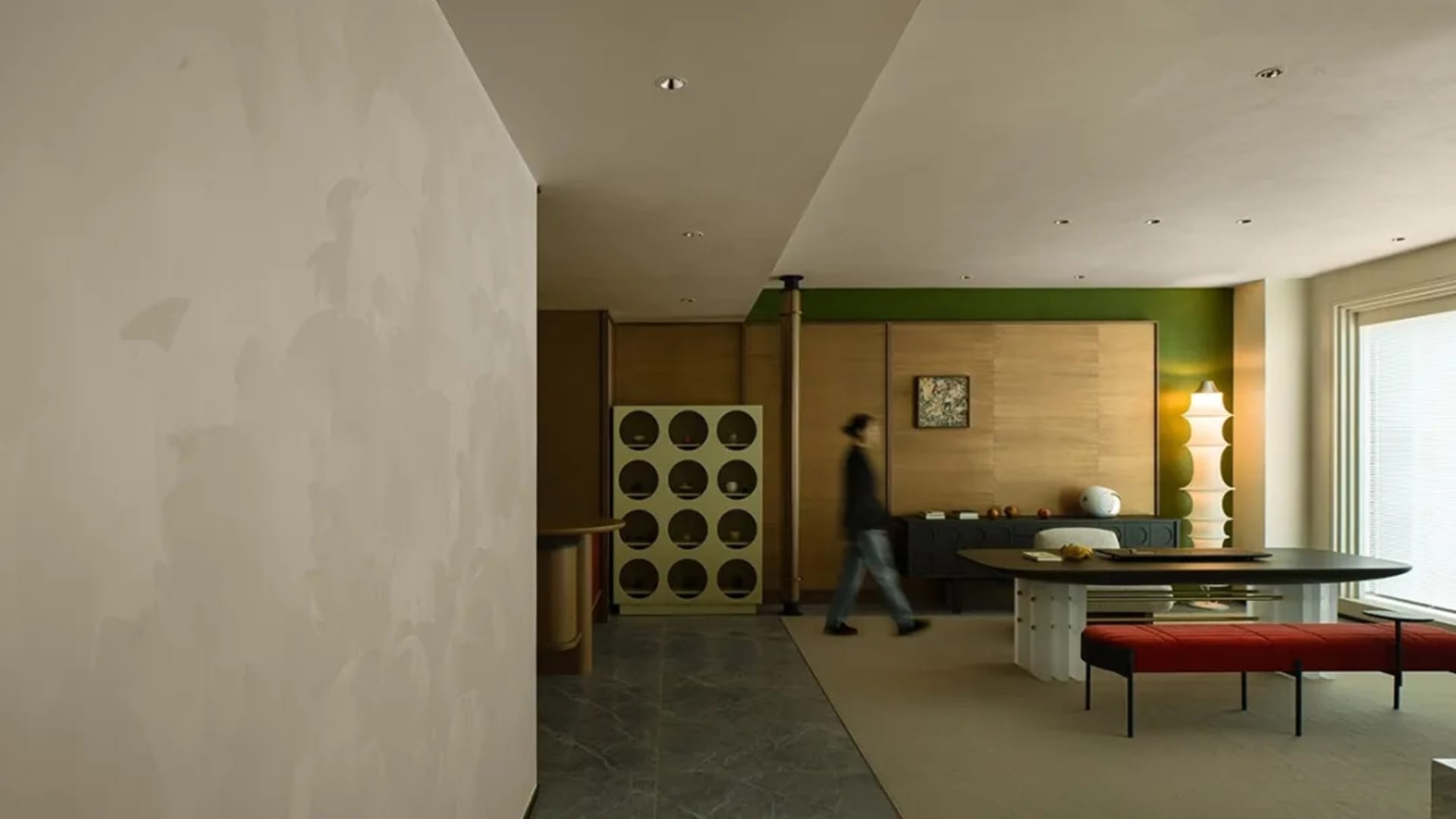 A modern living room with a concrete floor, green accent wall, and wooden furniture.