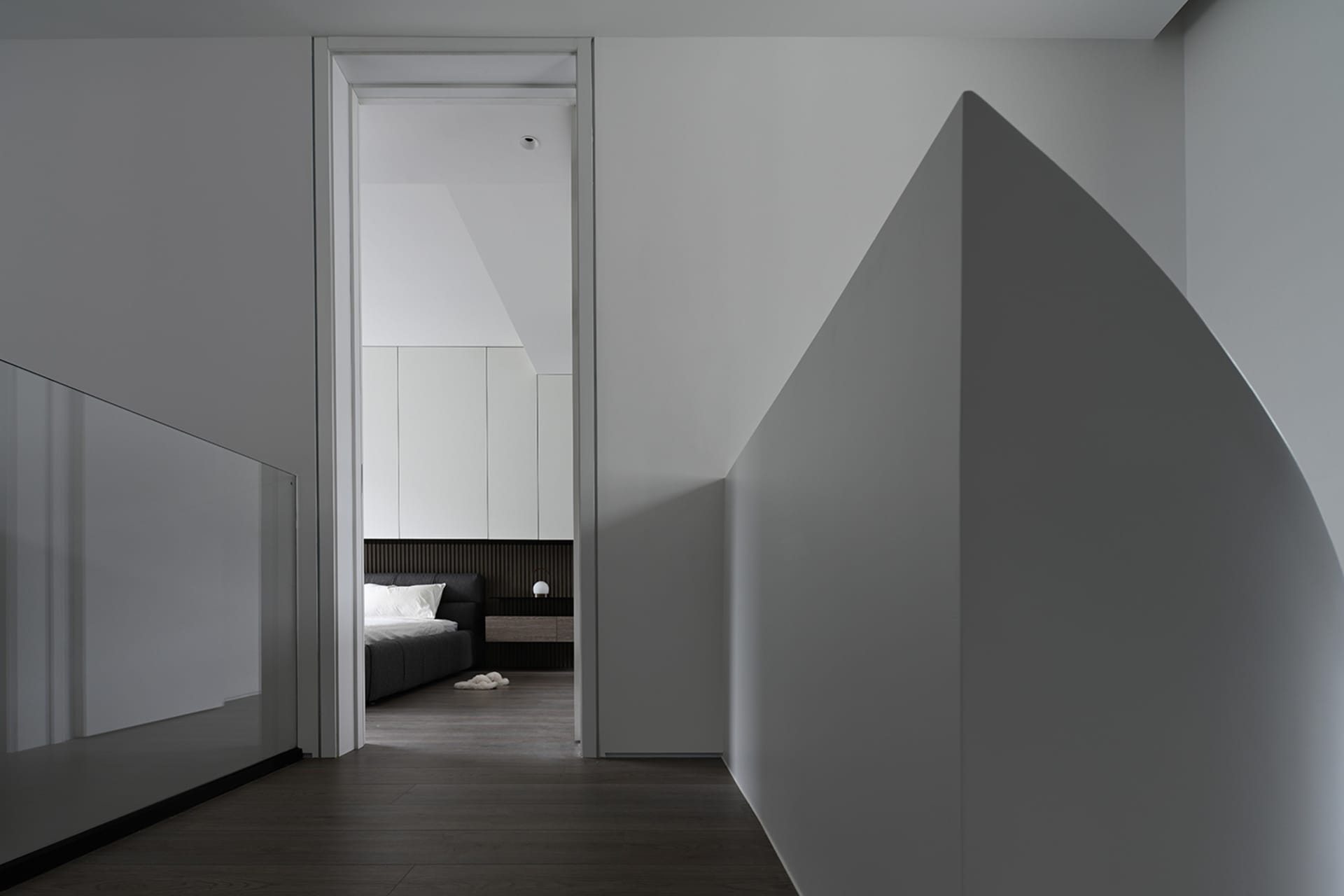 A modern bedroom featuring minimalist design with hidden contours, made from wood, glass, and concrete materials.