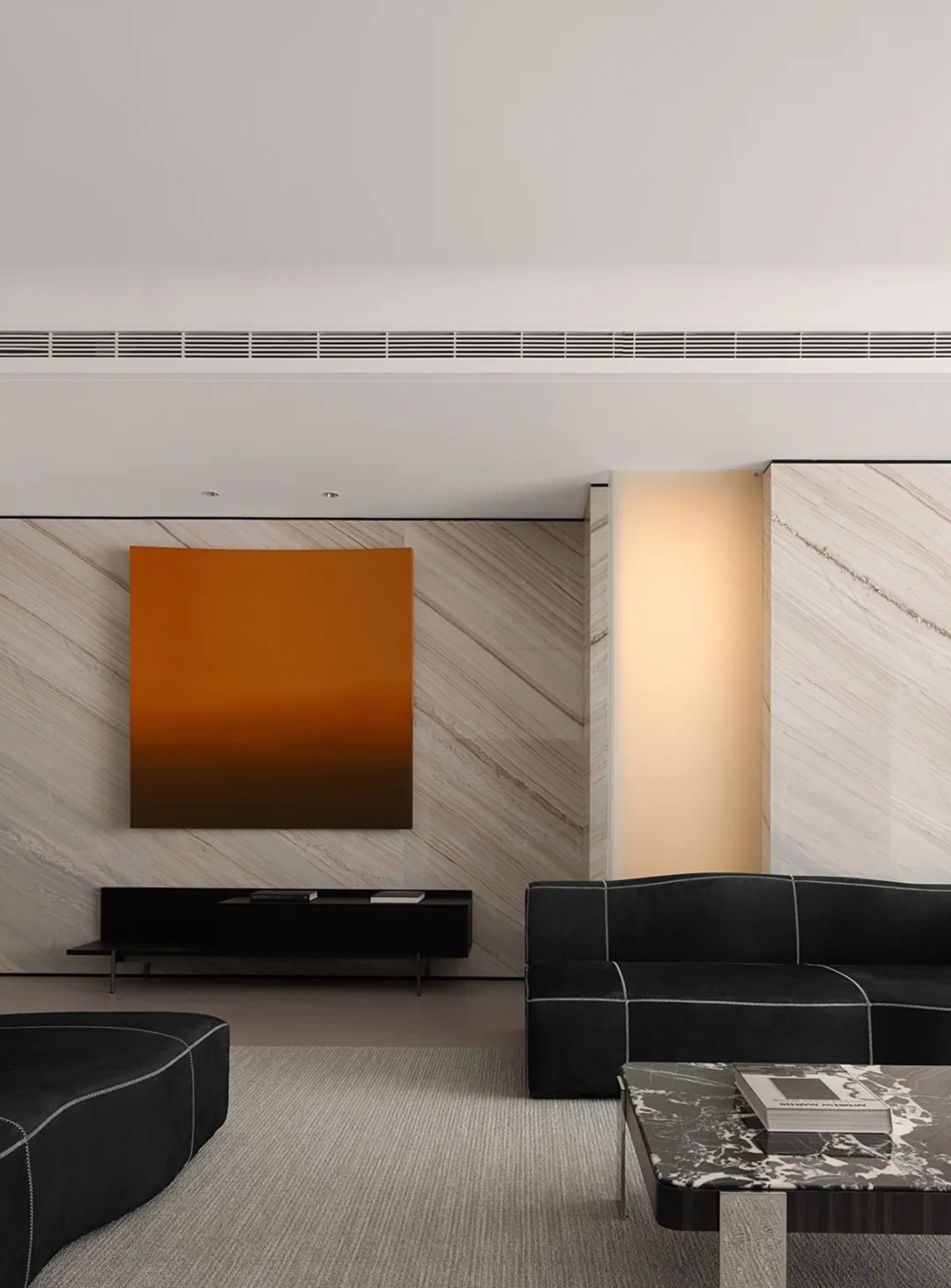 Modern living room with marble elements and sleek, black furniture.