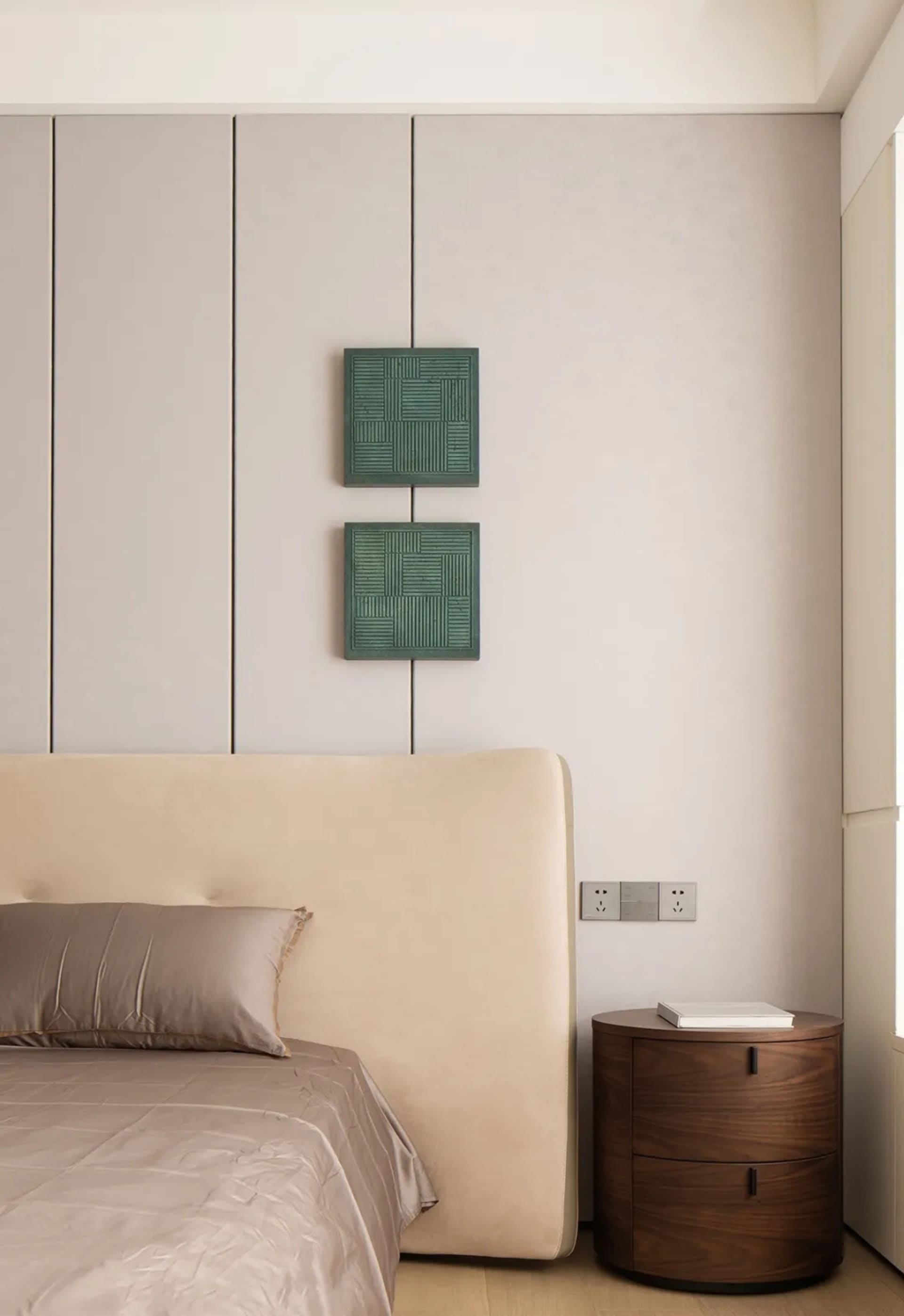 Modern minimalist bedroom featuring beige upholstered bed, green wall art, and wooden nightstand.