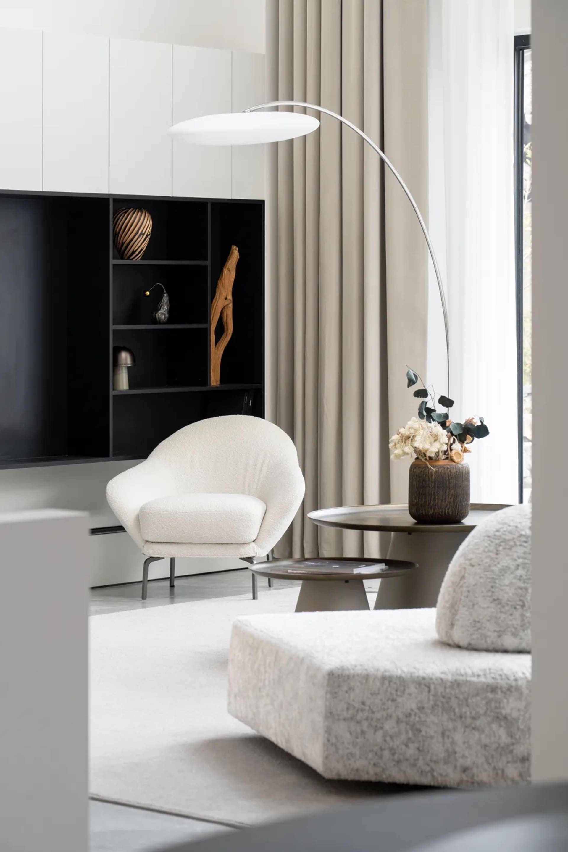 極簡客廳內擺放天鵝絨現代扶手椅、俐落落地燈,以及舒適腳凳,背景為木質牆面
