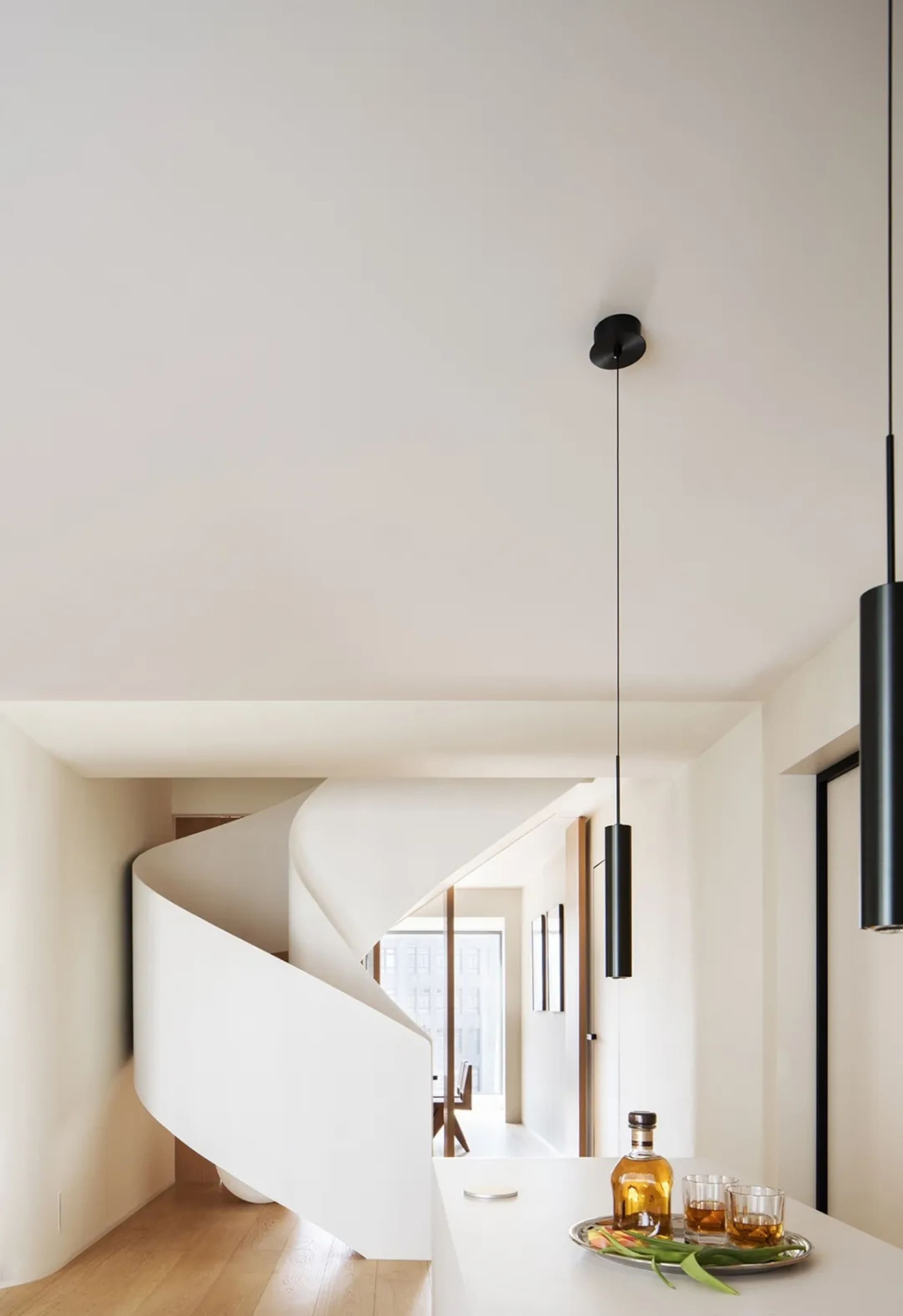A minimalist interior featuring a white concrete spiral staircase