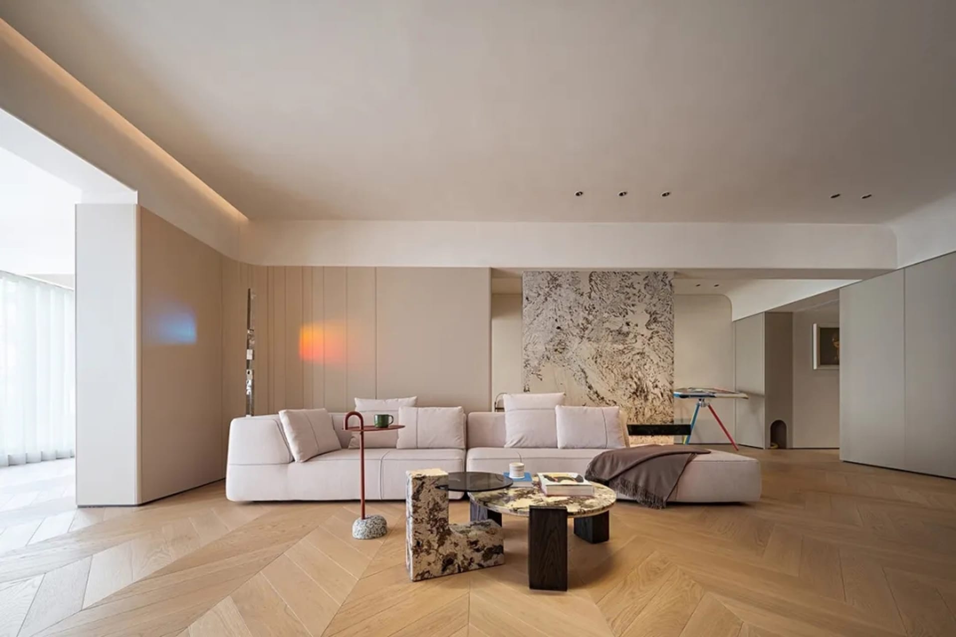 Modern minimalist living room with marble accent wall, wooden flooring, and concrete elements.