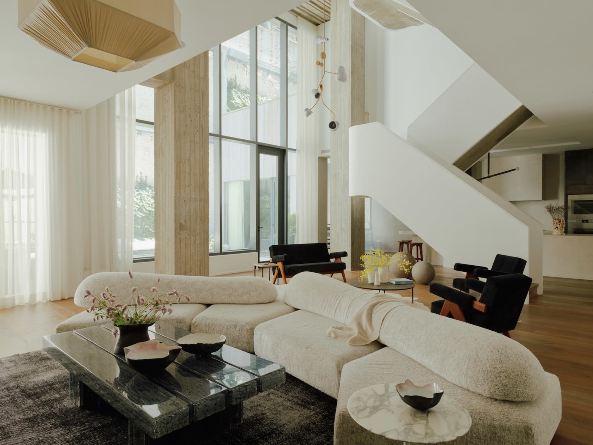 A modern living room with neutral-colored furnishings, large windows, and minimalist decor.